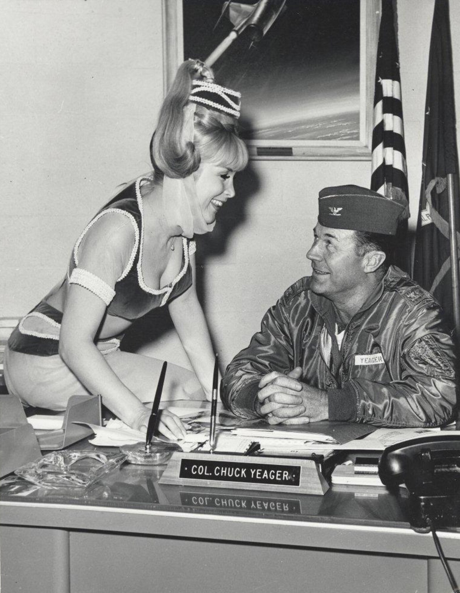 Then Col. Chuck Yeager visits with "I Dream of Jeannie" star, Barbara Eden in his office at the United States Aerospace Research Pilot School. The NF-104 painting, created in 1962 by British aviation artist, Douglas Ettridge is displayed behind Yeager's desk. Considered an important piece of USAF Test Pilot School history, the painting was restored by renowned aviation artist, historian, and author Mike Machat in February after extensive damage to the artwork was discovered while redecorating. (Courtesy Photo by Air Force Flight Test Center History Office)