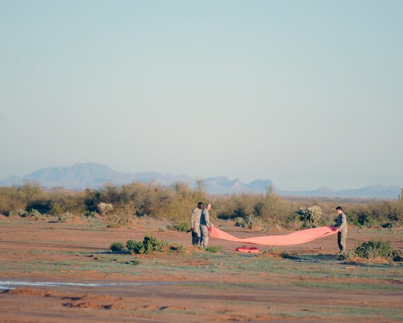 U.S. Air Force Airmen from the 58th Rescue Squadron at Nellis Air Force Base, Nev., designate a landing spot for pararescuemen and payloads Feb. 15, 2012, in Eloy, Ariz. Pararescuemen are able to control payloads as they descend using the Joint Precision Airdrop System.  (U.S. Air Force photo by Airman 1st Class Christine Griffiths/Released)
