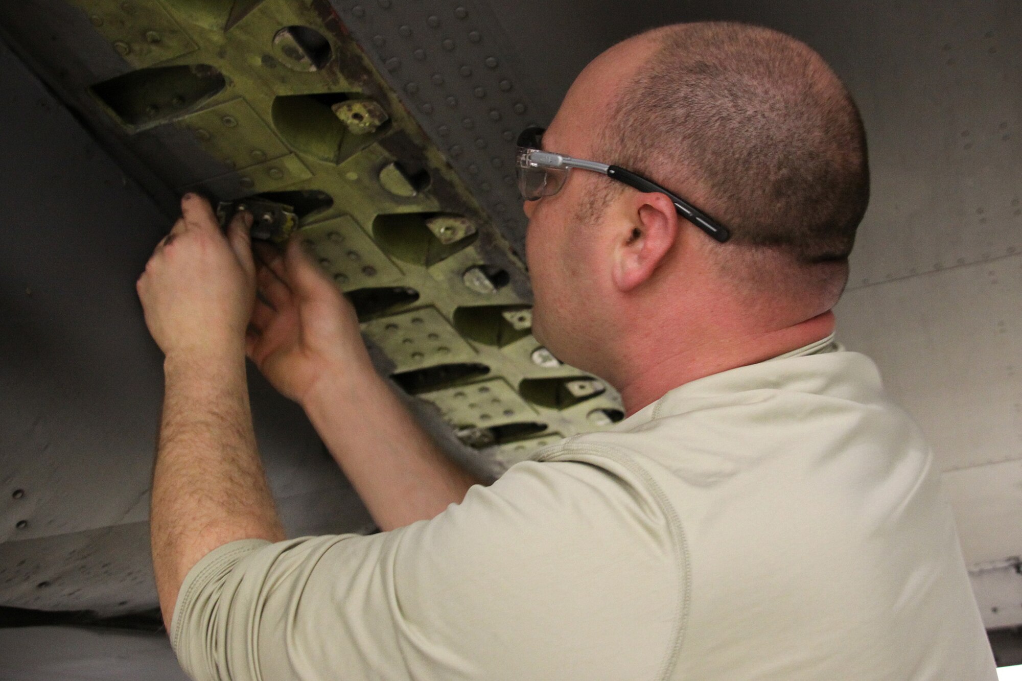 Tech. Sgt. Robert Sadlon, assistant crew chief, 911th Aircraft Maintenance Squadron, reinstalls a bracket that holds a sheet metal panel to the wing of a C-130, Jan. 6, 2012. The panel was removed for a routine non-destructive inspection, which includes checking the outer and inner pieces of the wing for cracks and corrosion. (U.S. Air Force Photo by Senior Airman Jonathan Hehnly\Released)