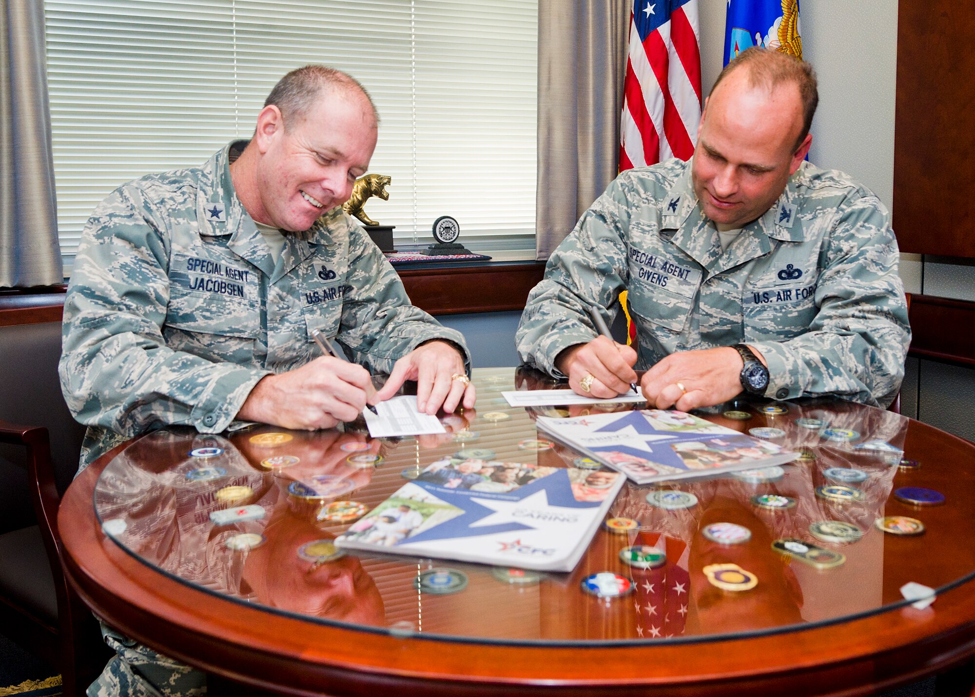 Brig. Gen. Kevin Jacobsen, OSI commander, left, and Col. Keith Givens, OSI vice commander, sign their CFC contribution forms at OSI headquarters. OSI HQ exceeded its unofficial CFC goal of $40,000 by more than $19,000 in the 2011 CFC season. (U.S. Air Force photo by Mr. Mike Hastings.)
