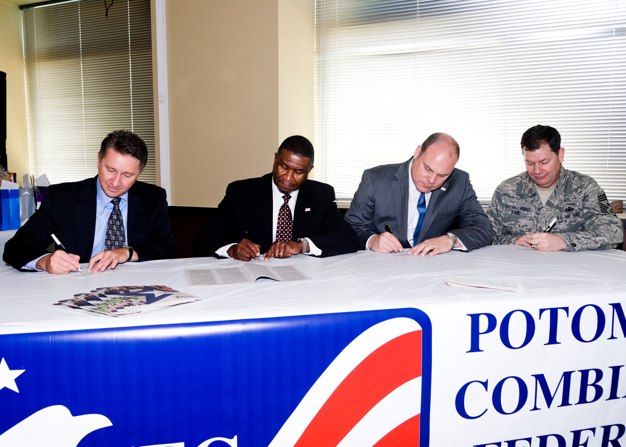 The Russell-Knox Building tenants at Quantico, Va., worked together to host a joint-Combined Federal Campaign event in the building's cafeteria. Members from the Air Force Office of Special Investigations, Naval Criminal Investigative Service, Army Criminal Investigative Service, the Defense Intelligence Agency and the Defense Security Service participated in the effort. Pictured here signing their CFC contribution forms are, from left, Mr. Michael Janosov, OSI executive director; Mr. Stan Sims, DSS director; Mr. James Kren, DSS deputy director, and Chief Master Sgt. John Fine, OSI command chief. CFC gives federal employees an opportunity to give back to the community and support various non-profit organizations. The CFC season runs from Sept. 1 through Dec. 15. (U.S. Air Force photo by Mr. Mike Hastings.)