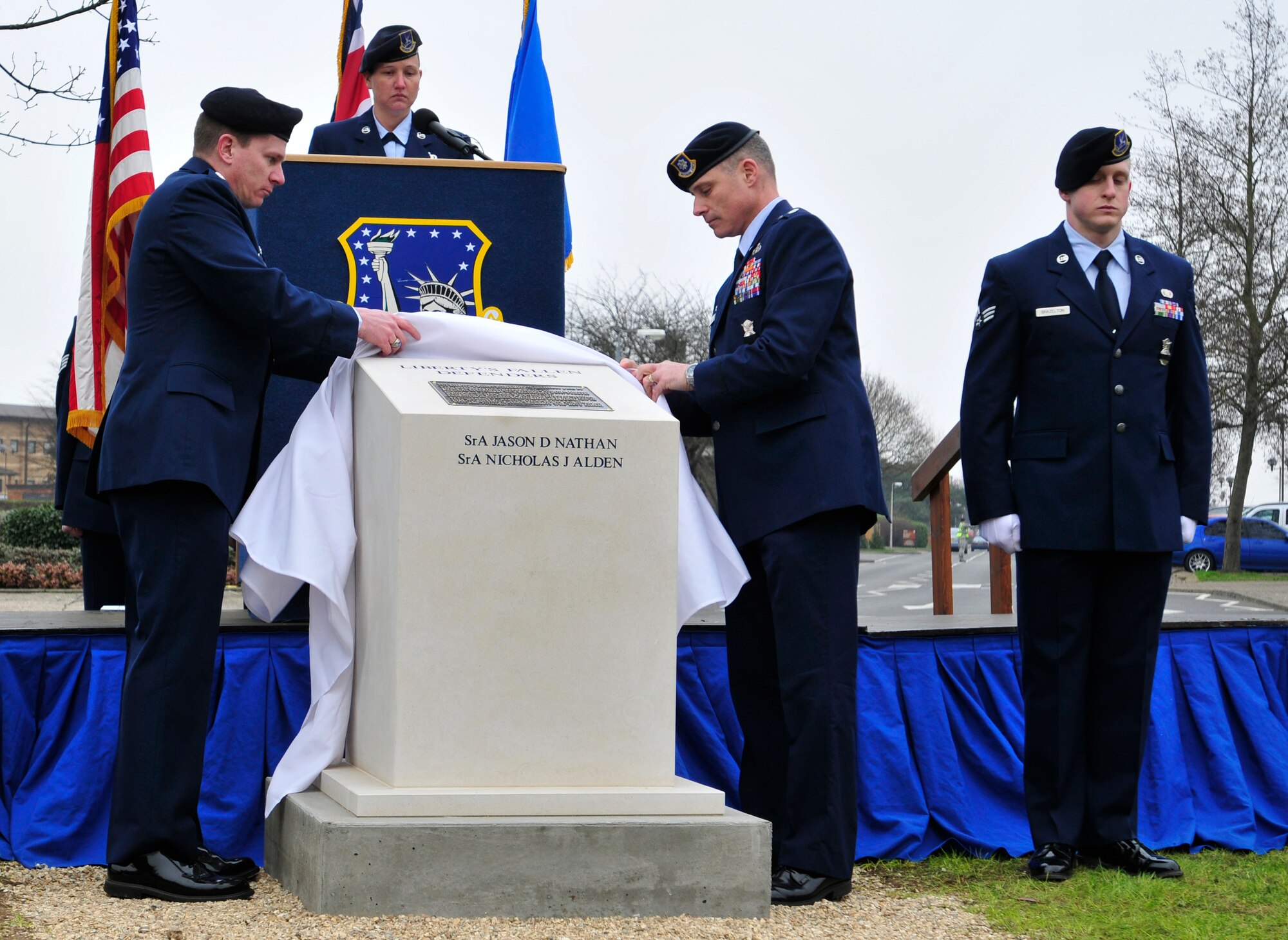 ROYAL AIR FORCE LAKENHEATH, England – (left to right)Lt. Col. Paul Cairney, 48th Security Forces Squadron commander, and Lt. Col. David Harris, 100th SFS commander,  unveil a stone monument honoring the memory of 48th SFS Senior Airmen Jason D. Nathan and Nicholas J. Alden during the dedication of the Liberty’s Fallen Defenders Memorial March 2, 2012. The ceremony was held on the one year anniversary of the shooting at Frankfurt International Airport, Germany. Nathan was killed in action while deployed to Iraq in June 2007. Alden was killed during the Frankfurt shooting while preparing to deploy to Afghanistan in March 2011. The monument serves as a reminder of all Liberty Defenders who have fallen since 2001. (U.S. Air Force photo by Senior Airman Tiffany M. Deuel)