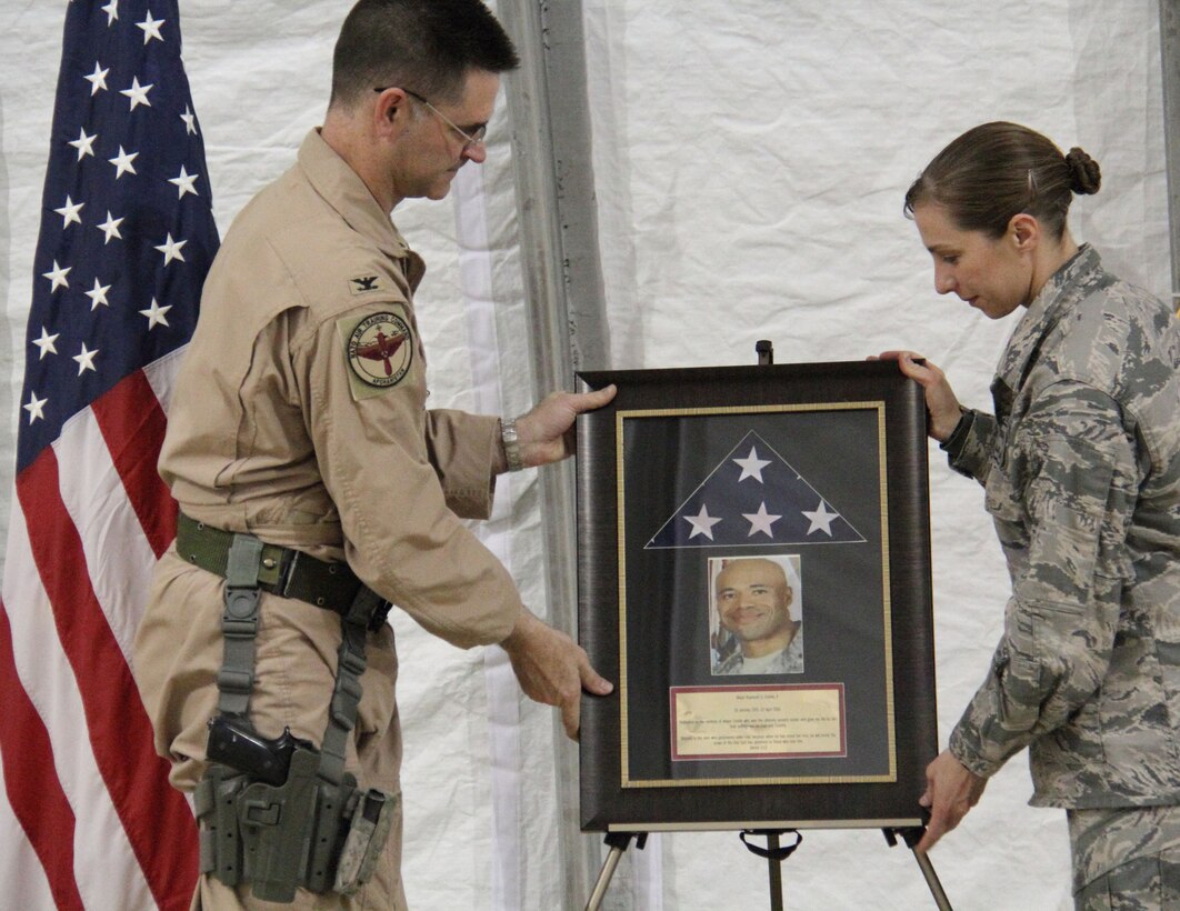 Air Force Col. John Hokaj, commander of the 838th Air Expeditionary Air Advisory Group, and Maj. Jessica Haugland, 838th AEAG communications adviser, display a plaque honoring Maj. Raymond Estelle during a dedication ceremony Feb, 27, 2011. Estelle lost his life April 27, 2011, during a shooting incident at the Afghan Command and Control Center in the Afghanistan air force headquarters, North Kabul International Airport. (Italian. air force photo by Tech. Sgt. My Luciano