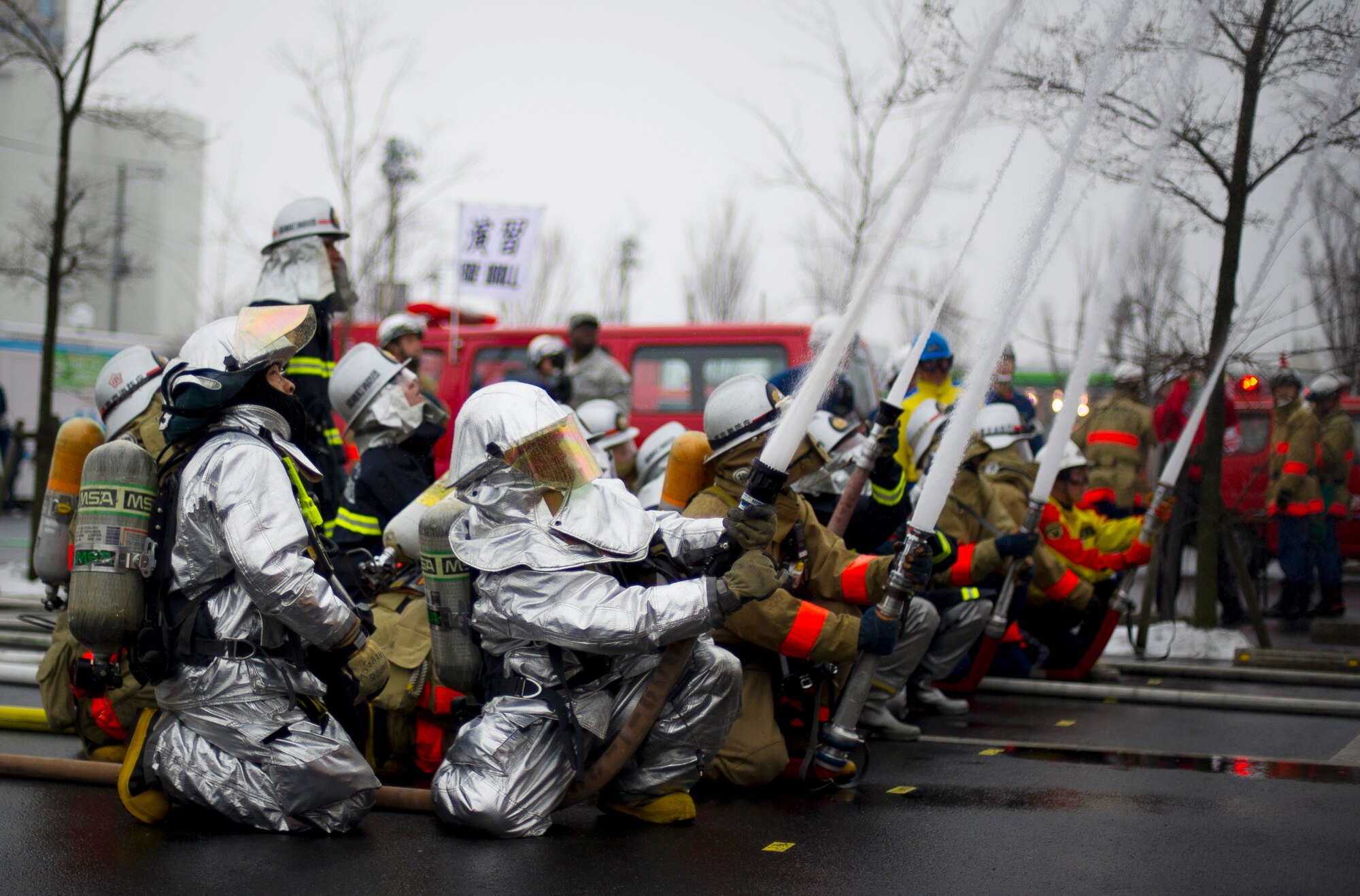 YOKOTA AIR BASE, Japan -- Japanese firefighters from Fussa, Hamura, Mizuho and Yokota Air Base, simulate extinguishing a burning building during the Fussa Fire Department Rescue Response Exercise outside a Japanese department store, March 2, 2012. More than 130 firefighters participated in the event. (U.S. Air Force photo/Staff Sgt. Chad C. Strohmeyer)