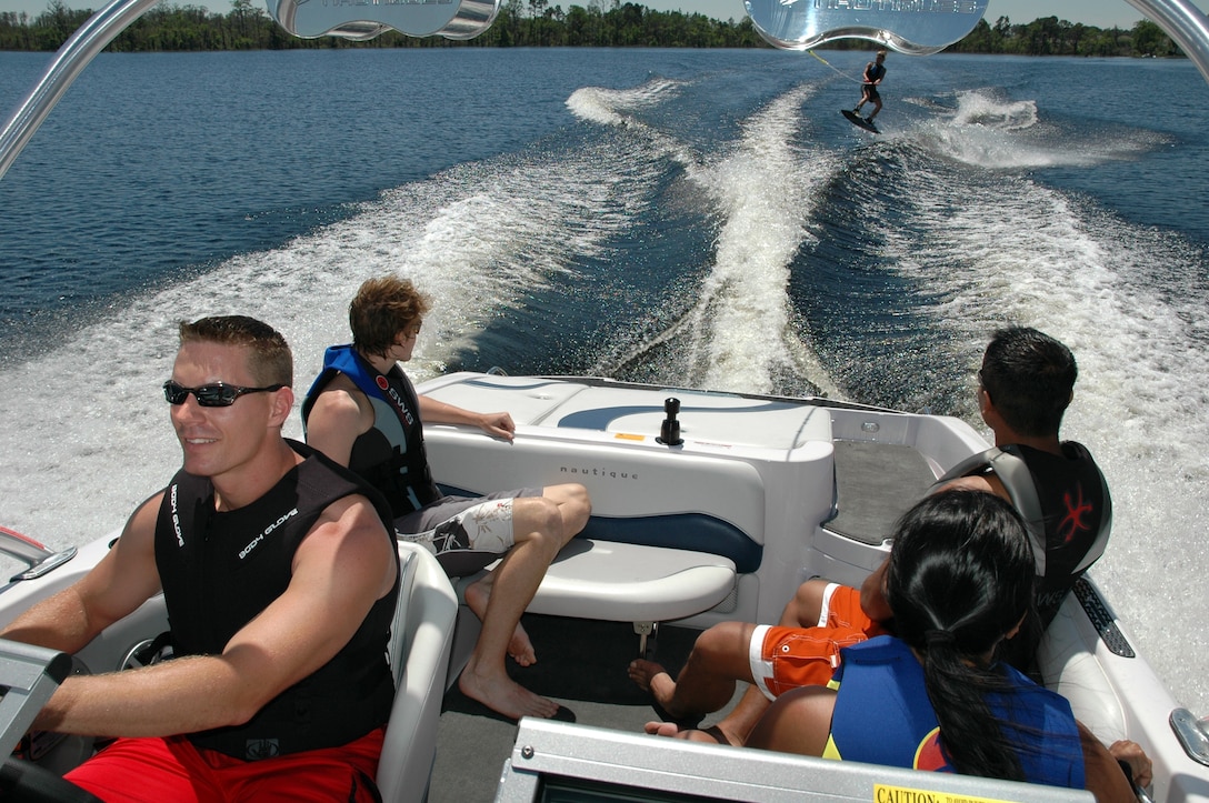 A group of friends enjoy waterskiing and boating while wearing their lifejackets.