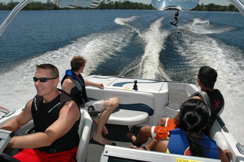 A group of friends enjoy waterskiing and boating while wearing their lifejackets.
