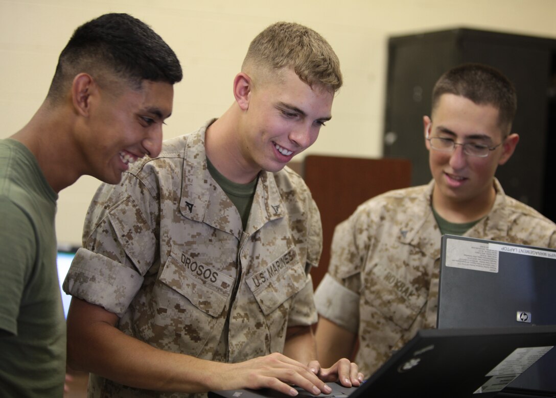 Lance Cpl. Kevin D. Drosos, a data network specialist with Cyber Platoon, Communications Company, Headquarters Battalion, 2nd Marine Division, types commands on a network computer while troubleshooting for fellow specialists aboard Marine Corps Base Camp Lejeune, N.C., July 27, 2011. Lance Cpl. Andres E. Roybal (right), a fellow data network specialist, follows along with him as well as Pvt. Javier Gonzalez.