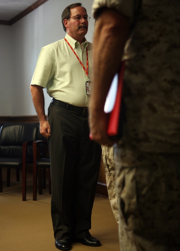 Dennis Douthett, the II MEF training officer, stands at the position of attention while his citation is read before being awarded the Navy Meritorious Civilian Service Medal, July 21, 2011, aboard Marine Corps Base Camp Lejeune, N.C. For almost a decade, Douthett has worked with the II MEF Communications Security Office, which works to protect our nation’s secrets from our adversaries.