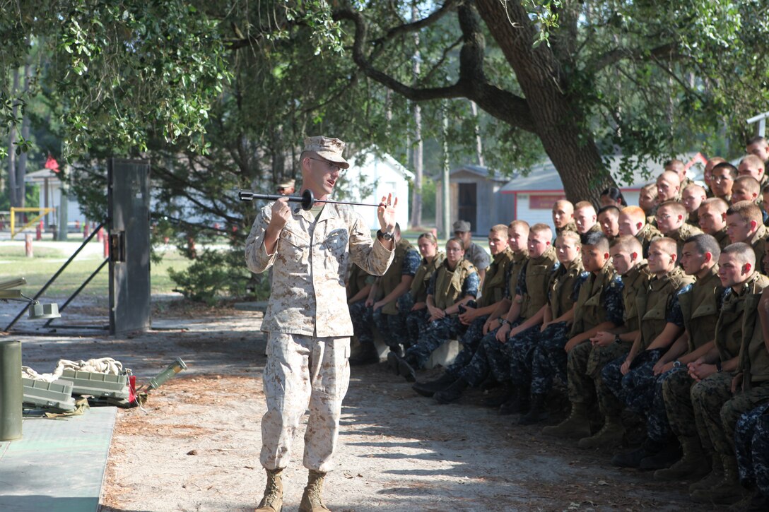 Gunnery Sgt. Michael Baehr, section head of explosive hazards, with Combat Engineer Instruction Company, Marine Corps Engineer School, shows the midshipmen a shaped charge that the Israeli forces use with their rifles, during a stop at the Engineer School as part of the midshipmen’s weeklong Career Orientation and Training for Midshipmen program aboard the base. The midshipmen toured the base and rappelled down towers, rode in amphibious assault vehicles and got to understand the way the Marine Corps works and a Marine’s daily life.