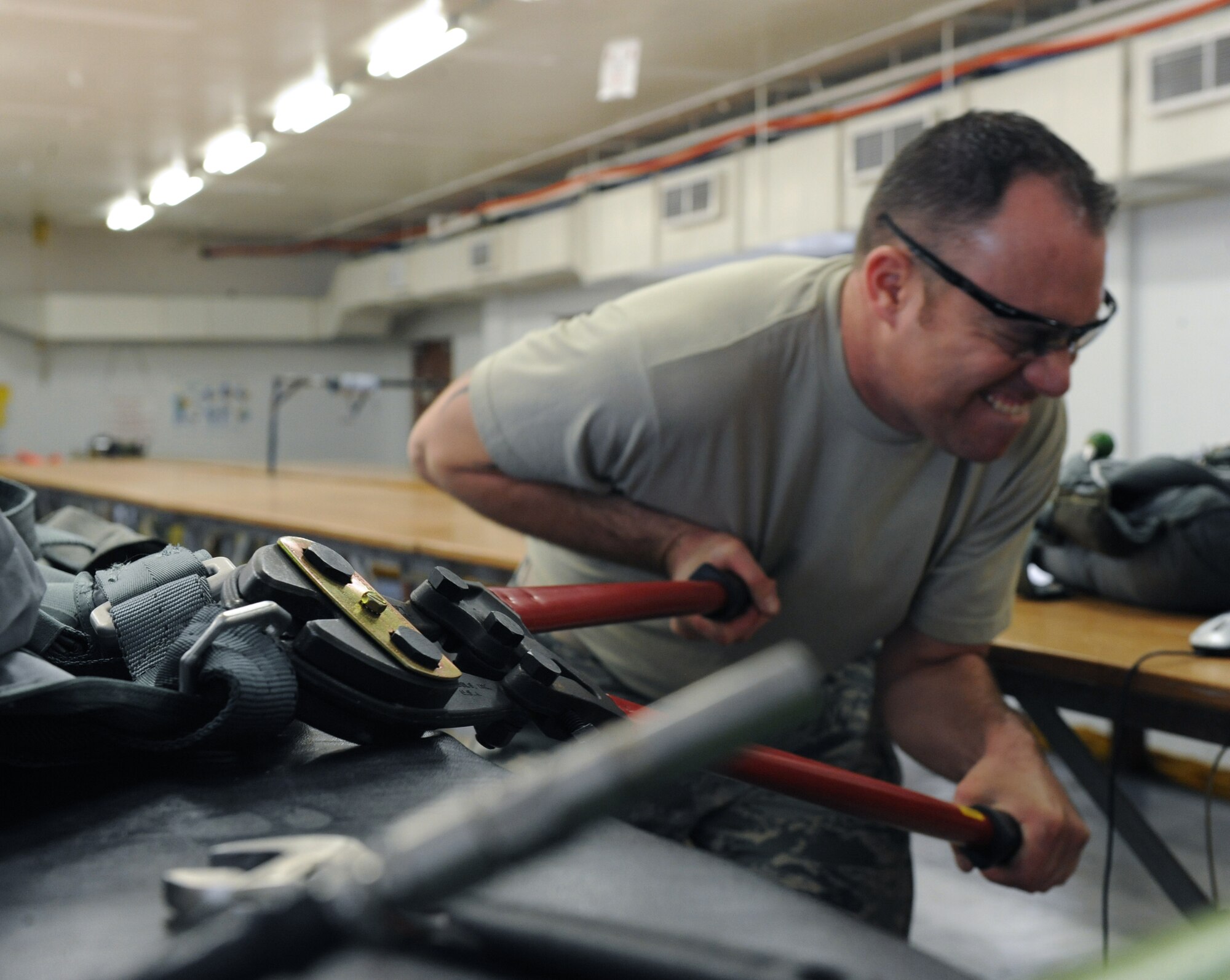 Tech. Sgt. Marcus Kelley, 2nd Operation Support Squadron aircrew flight equipment, uses a bolt cutter to cut a D-ring on Barksdale Air Force Base, La., March 6. Most of the equipment removed from a parachute harness rebuild are inspected and attached to a new harness. (U.S. Air Force photo/Airman 1st Class Micaiah Anthony)(RELEASED)