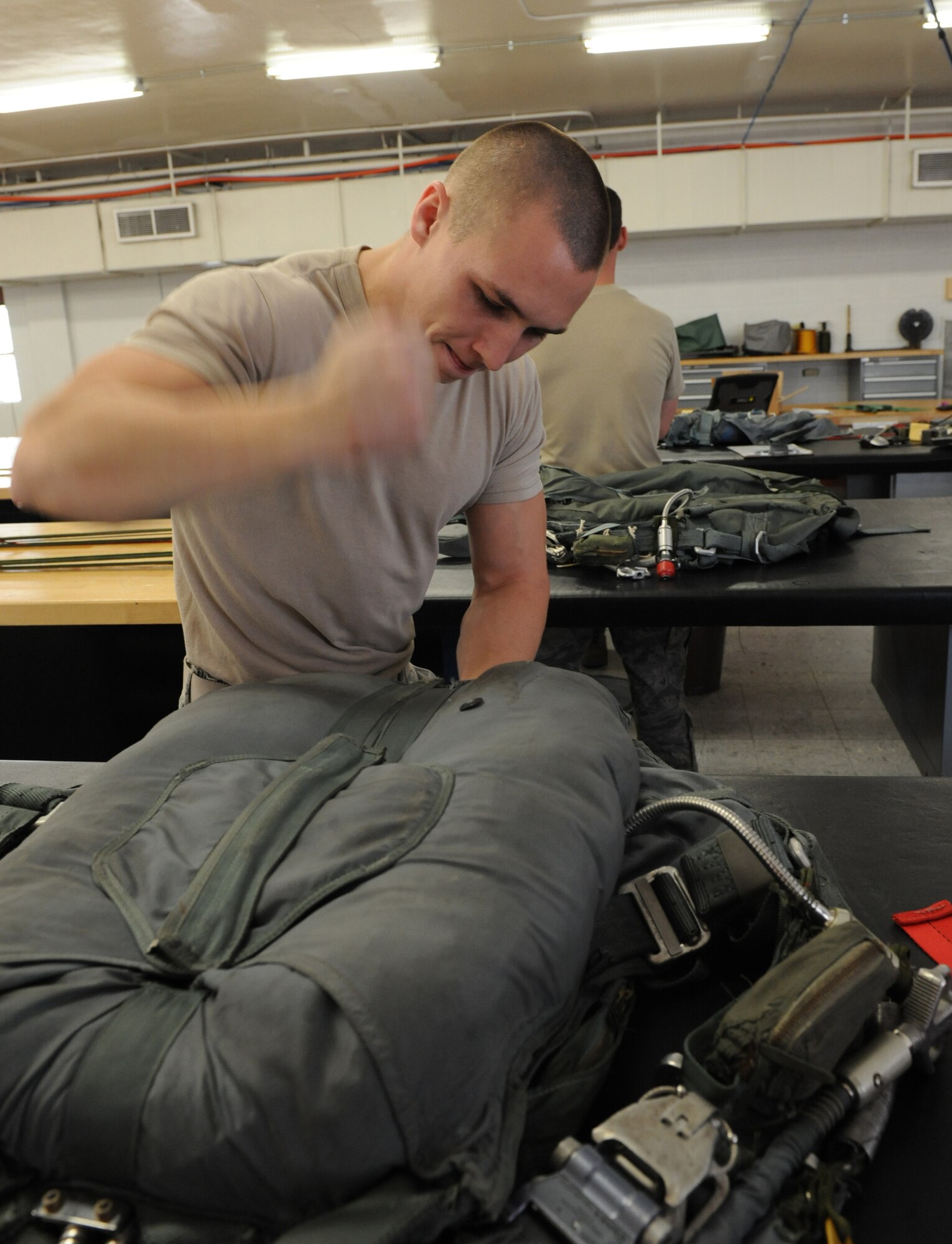 Senior Airman Blake Hill, 2nd Operation Support Squadron aircrew flight equipment, flattens a parachute on Barksdale Air Force Base, La., March 6. If an aircrew member lands in the water wearing a parachute, the chute will automatically detach itself from the wearer once the sensor becomes wet. (U.S. Air Force photo/Airman 1st Class Micaiah Anthony)(RELEASED)