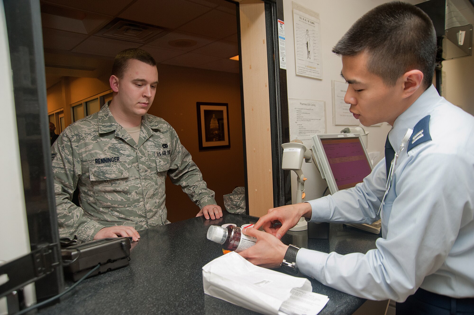 Capt. Truong-Vinh Phung, 779th Medical Support Squadron pharmacist, gives Senior Airman Harry Renninger, 11th Logistics Readiness Squadron vehicle operator, directions on medicine dosage during patient check-in at the Malcolm Grow Medical Center’s Main Pharmacy on March 6. (Photo/Bobby Jones)