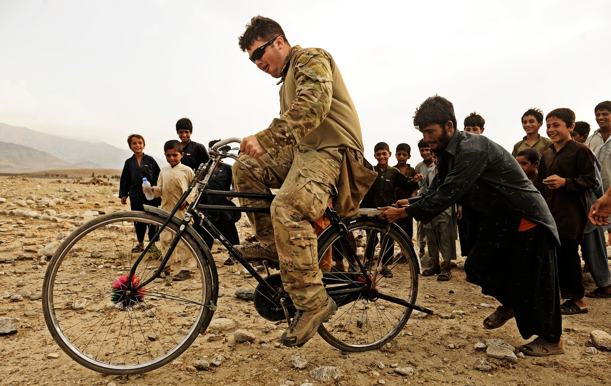 Lucas Simmons, team leader attached to Laghman Provincial Reconstruction Team, rides a bike given to him by a local child during a multi-day operation Aug. 21 in Alingar District, Laghman Province. The PRT, combined with assets from the 45th Infantry Brigade, conducted a cordon and search in a village thought to be home to IED makers and Taliban fighters. (U.S. Air Force photo/ Staff Sgt. Ryan Crane)
