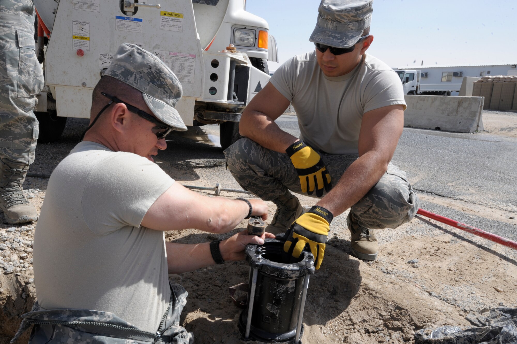 Staff Sgt. Antonio Martinez (left) and Senior Airman Joel Mendoza, 332nd Expeditionary Civil Engineer Squadron utilities shop members, tighten a dresser coupling at an undisclosed location in Southwest Asia, March 7, 2012. The coupling is used to connect two pieces of a water pipeline. Martinez is deployed from Peterson Air Force Base, Colo., and is a Florida native. Mendoza is deployed from Fairchild Air Force Base, Wash., and is a native of Ft. Lauderdale, Fla. (U.S. Air Force photo by Staff Sgt. Joshua J. Garcia/Released)
