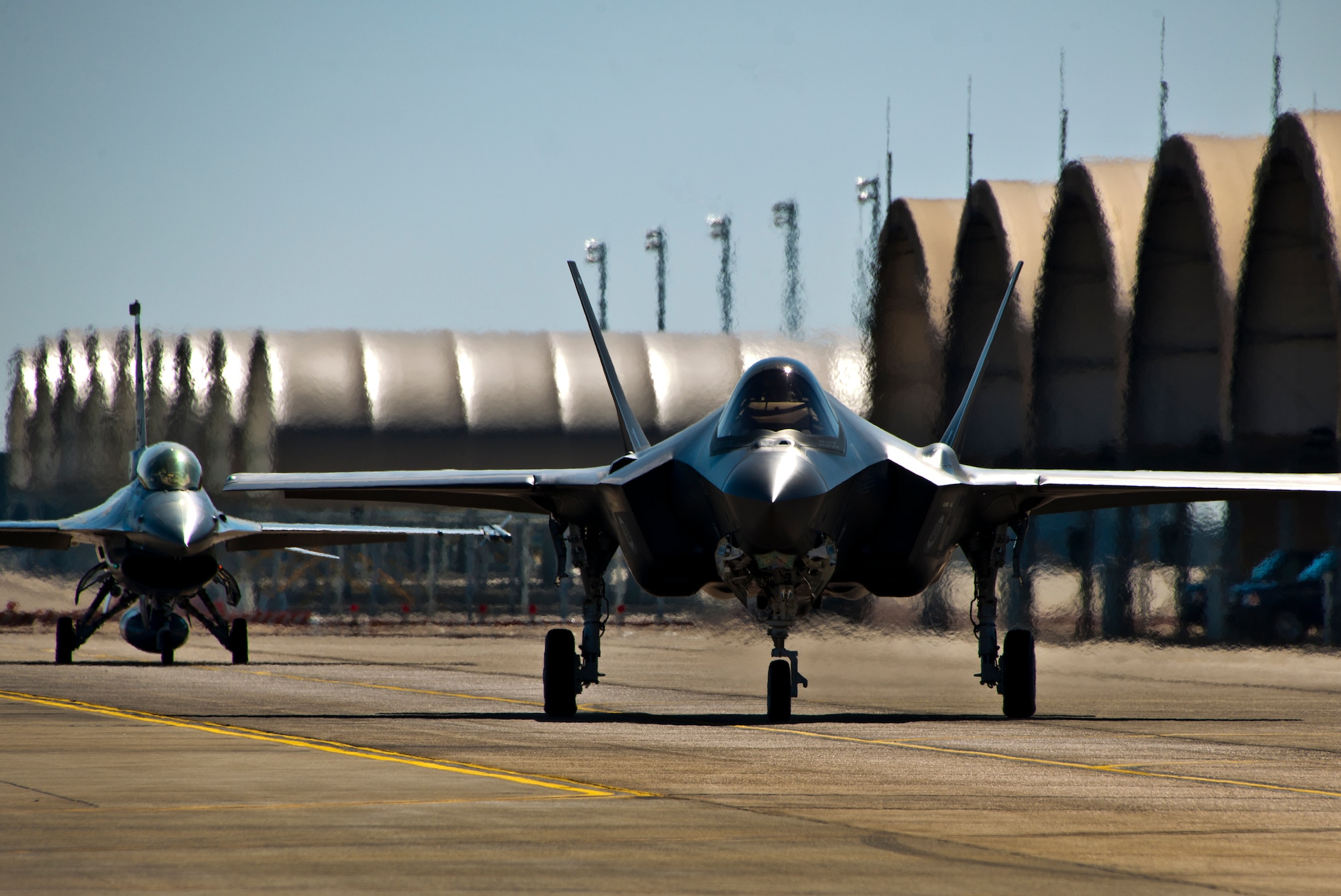 The F-35A Lightning II joint strike fighter taxis out for its first training sortie followed by an F-16 chase aircraft March 6 at Eglin Air Force Base, Fla. (U.S. Air Force photo/Samuel King Jr.)