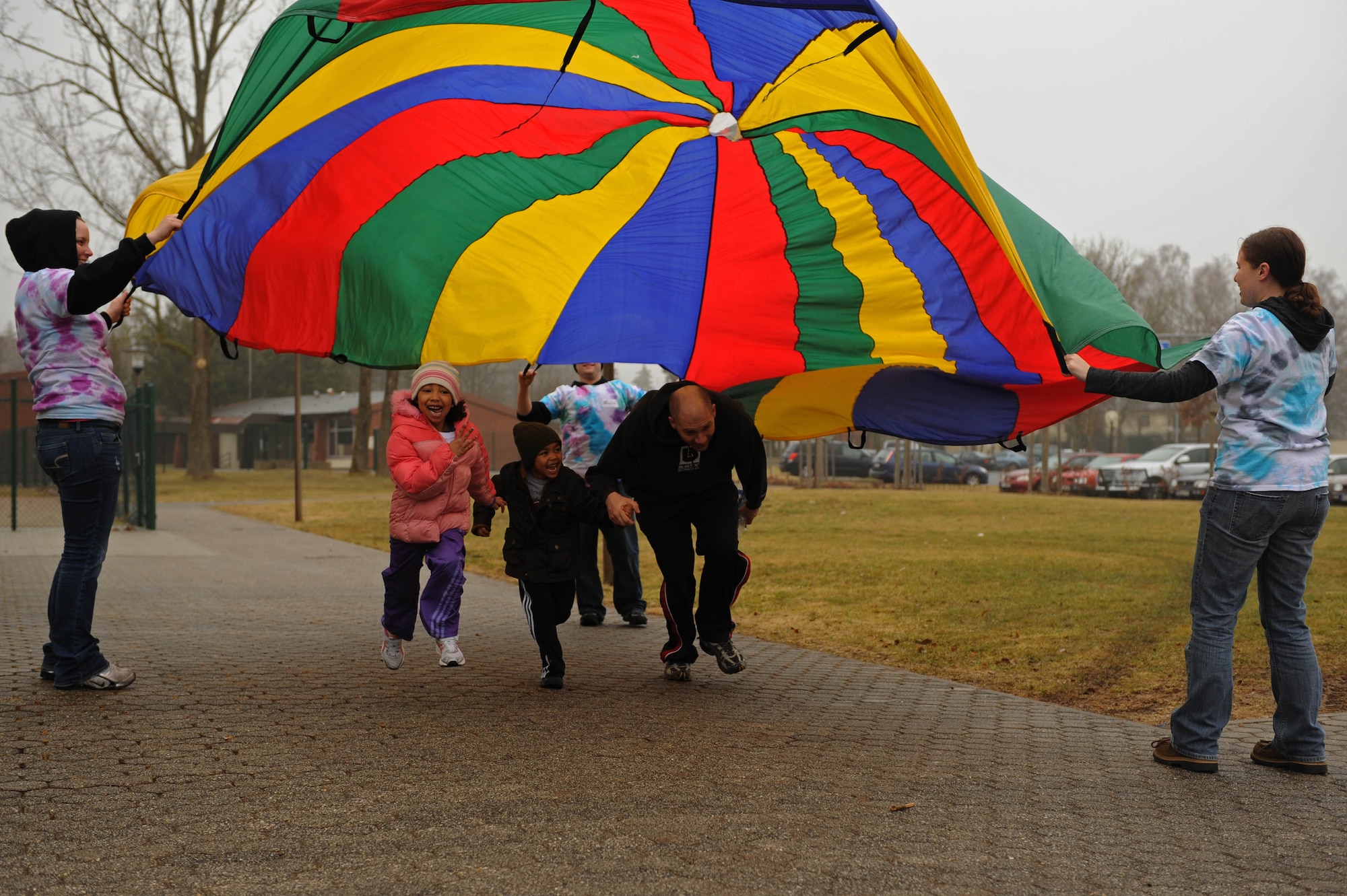 SPANGDAHLEM AIR BASE, Germany – Master Sgt. Alex Stepp, 52nd Aircraft Maintenance Squadron, runs with his son, Hayden, and daughter, Amaya, under a parachute during the FitFactor X-Games event at the Spangdahlem Middle School here March 3. The 52nd Force Support Squadron Youth Programs sponsored the event to introduce and familiarize students and their parents with fitness and health initiatives. FitFactor is an Air Force-wide youth fitness and health program that challenges children age 6 to 18 to be active for an hour each day, eat right and make healthy lifestyle choices. (U.S. Air Force photo by Airman 1st Class Matthew B. Fredericks/Released)