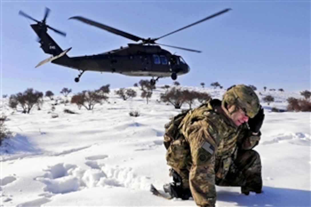 U.S. Army Sgt. 1st Class Shawn Joyce shields his face from blowing snow and other debris as a UH-60 Black Hawk helicopter lands nearby in Afghanistan's Parwan province, on March 1, 2012.  Joyce is a career counselor assigned to Task Force Poseidon.  