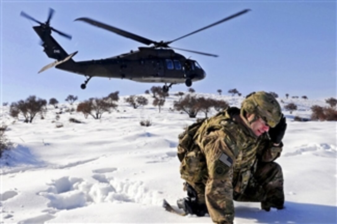 U.S. Army Sgt. 1st Class Shawn Joyce shields his face from blowing snow and other debris as a UH-60 Black Hawk helicopter lands nearby in Afghanistan's Parwan province, on March 1, 2012.  Joyce is a career counselor assigned to Task Force Poseidon.  