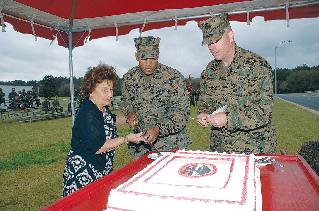 Mary Deiter, the wife of Karl Deiter, who was the first Marine stationed in Albany, joins Col. Terry V. Williams, commanding officer, Marine Corps Logistics Base Albany, center, and Sgt. Maj. Conrad Potts, sergeant major, MCLB Albany, in cutting the ceremonial cake in honor of the base’s 60th anniversary at Schmid Field, March 1.