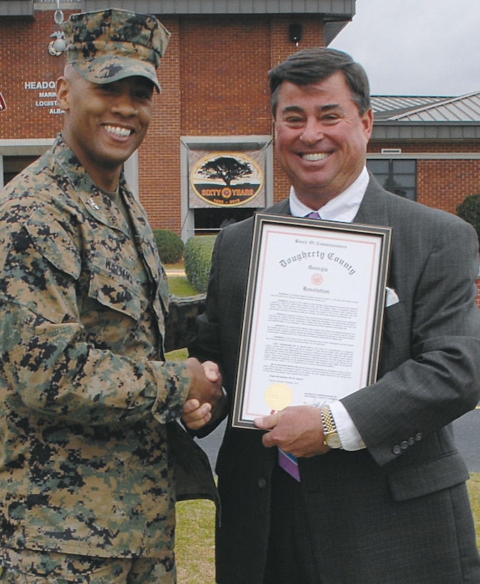 Col. Terry V. Williams, left, commanding officer, Marine Corps Logistics Base Albany, shakes hands with Jeff Sinyard, commission chairman, Dougherty County, at Schmid Field, March 1. Sinyard spoke at the base’s 60th anniversary and presented a proclamation to Williams.