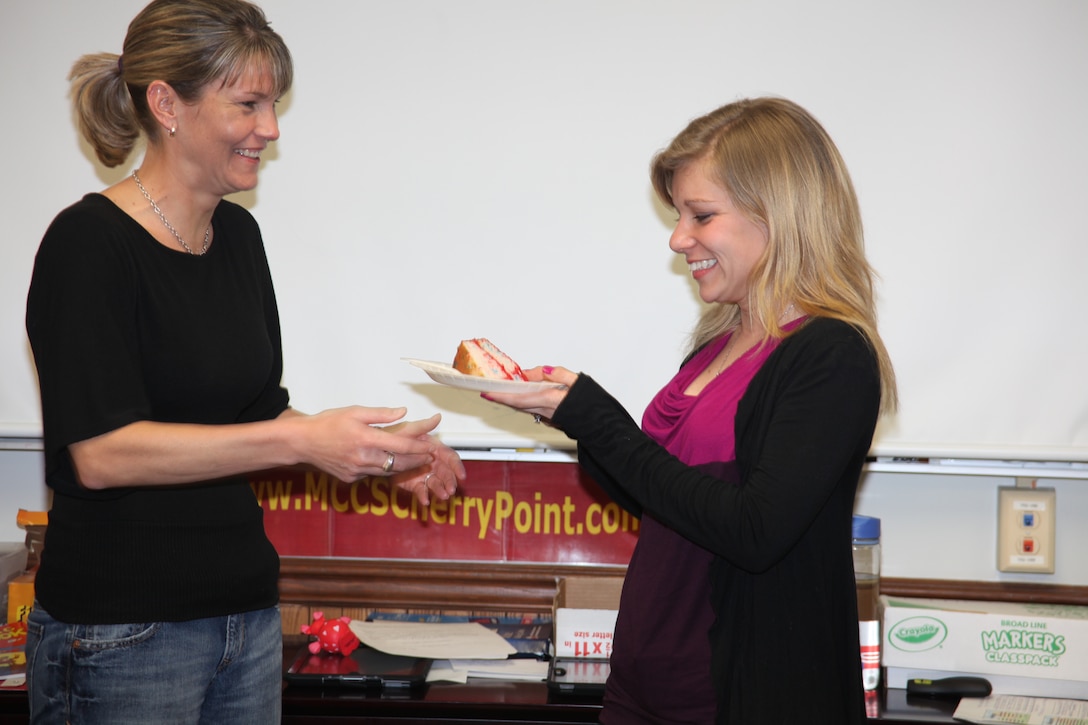 Much like a Marine Corps birthday ball tradition, Tara McDonald, left, the most senior Marine Corps spouse at the class, gives the first slice of cake to Anastasia A. Hastie, the youngest spouse, during the closing ceremony of the LINKS for Spouses class March 8. The Marine Corps Ball tradition of the cake being exchanged is a symbolic gesture of the passing on of knowledge and wisdom from the most senior to junior Marine, and the youngest passes the second as a sign of respect.