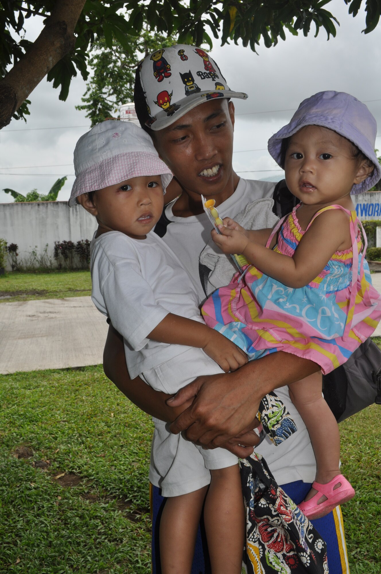 A Filipino father patiently waits with his two children while his wife receives medical care during the first day of Operation Pacific Angel-Philippines on March 5, 2012, in Legazpi City, Philippines. PACANGEL is a joint and combined humanitarian operation led by 13th Air Force. It is scheduled to run through March 10.(U.S. Air Force photo/Master Sgt. Allison Day)