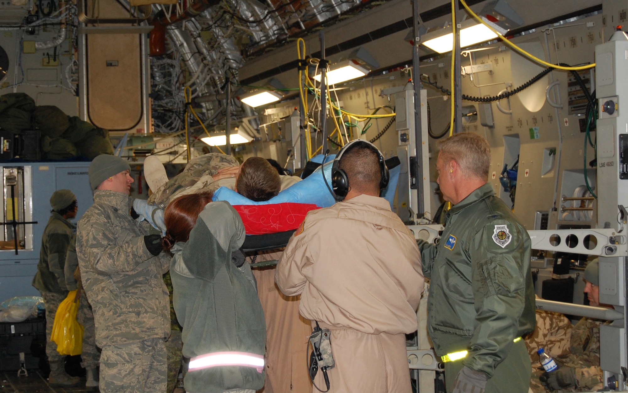 Wing leadership from the 920th Rescue Wing, Patrick Air Force Base, Fla., assist deployed medical Reservists transport a wounded warrior from a C-17 Globemaster III cargo aircraft to an awaiting bus for transport to a larger medical facility. These Rescue Airmen from the 920th RQW are members of the 920th Aeromedical Staging Squadron, and are deployed regularly to supplement active duty. Of the members performing the life-saving tasks daily, 25% are active duty and the rest are Reserve and Guard members. (U.S. Air Force photo/Col. (Dr.) Richard Huot)