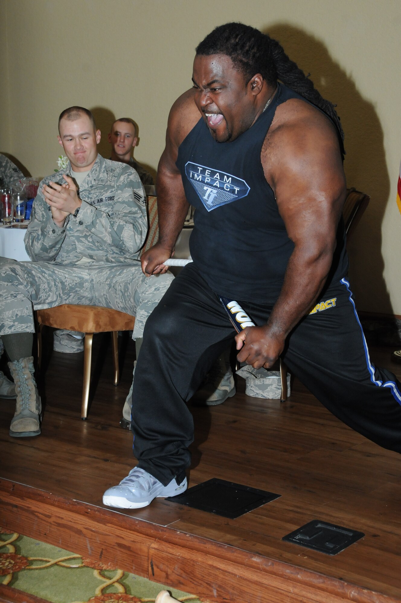 Randall Harris, Team Impact leader, bends a metal baseball bat across his leg during  the team’s performance at Keesler’s National Prayer Breakfast ceremony March 6, 2012, at the Bay Breeze Event Center, Keesler Air Force Base, Miss.  (U.S. Air Force photo by Kemberly Groue)