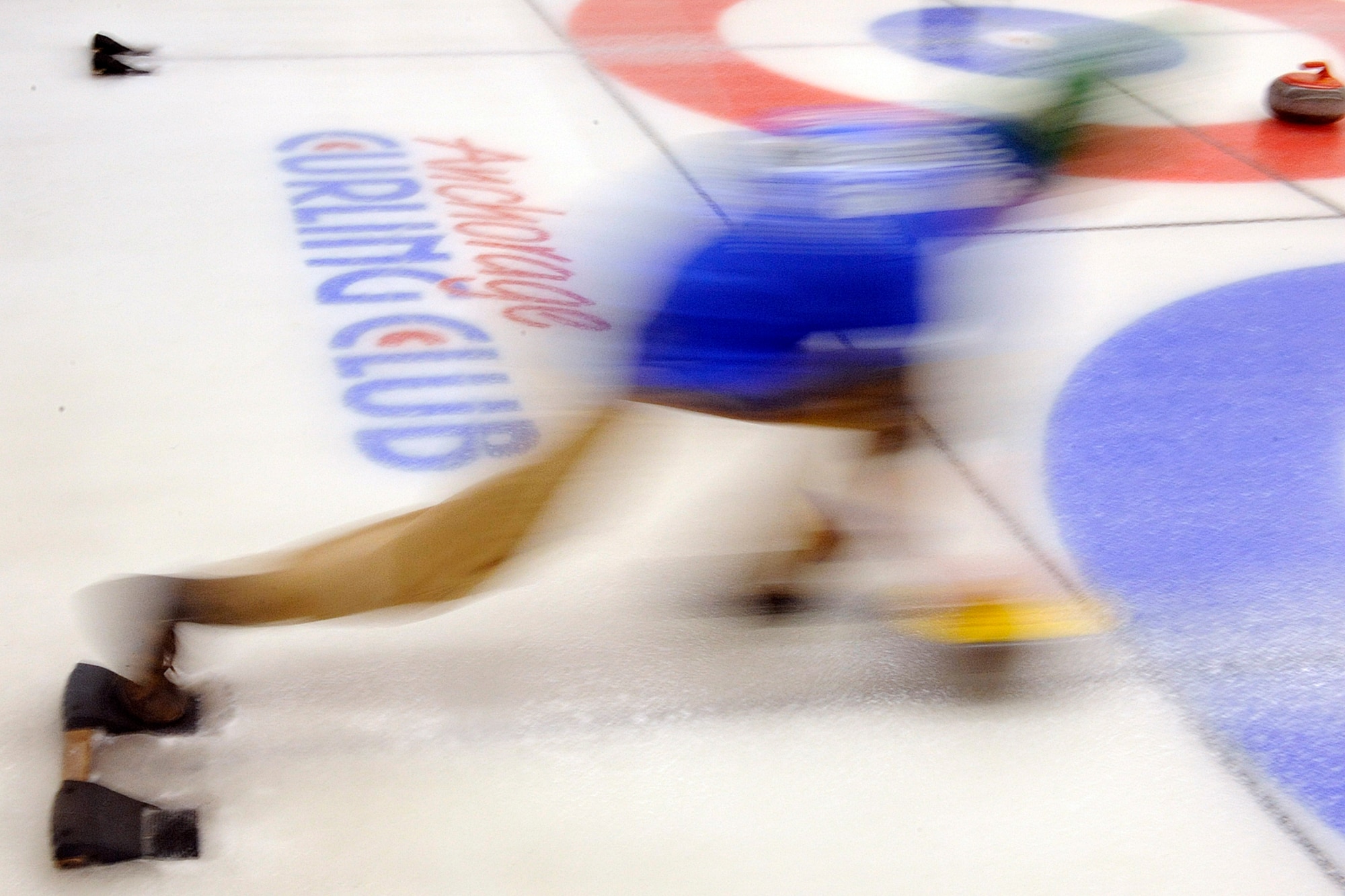 A slow shutter speed shows the motion as Capt. Brett Vongroven, 525th Fighter Squadron, launches a shot in the 3rd Wing curling competition at the Anchorage Curling Club March 2. (U.S. Air Force photo/John Pennell)