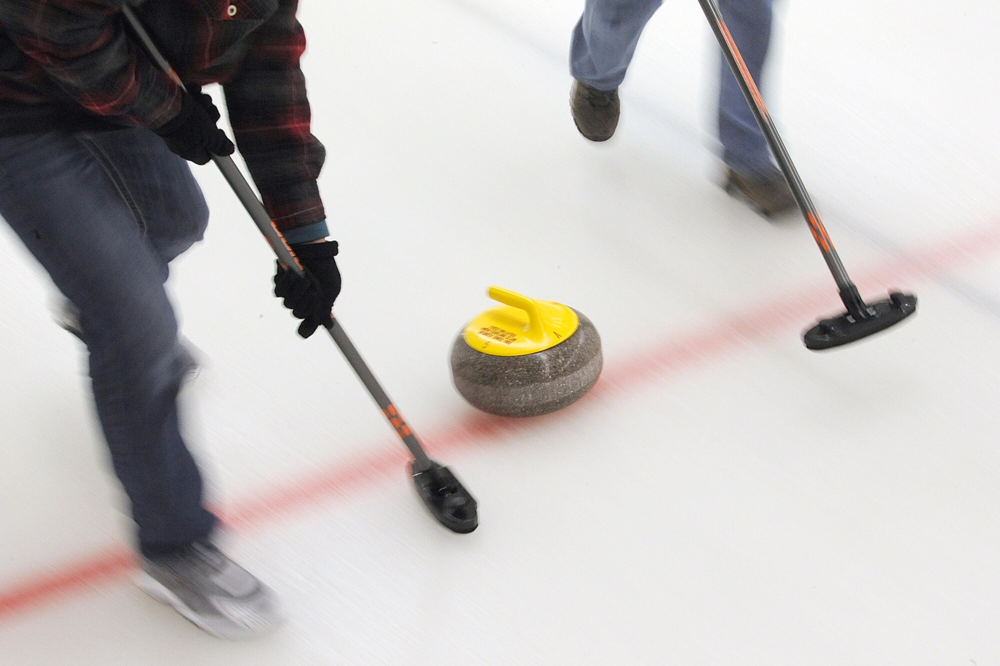 Sweepers from the 962nd AACS follow a stone as it slides across the ice during the championship game of the 3rd Wing curling competition March 2 at the Anchorage Curling Club. All eight 3rd Wing squadrons provided five-person teams to take part in the friendly competition. The winning team came from the Royal Canadian Air Force contingent of the 962nd AACS. (U.S. Air Force photo/John Pennell)