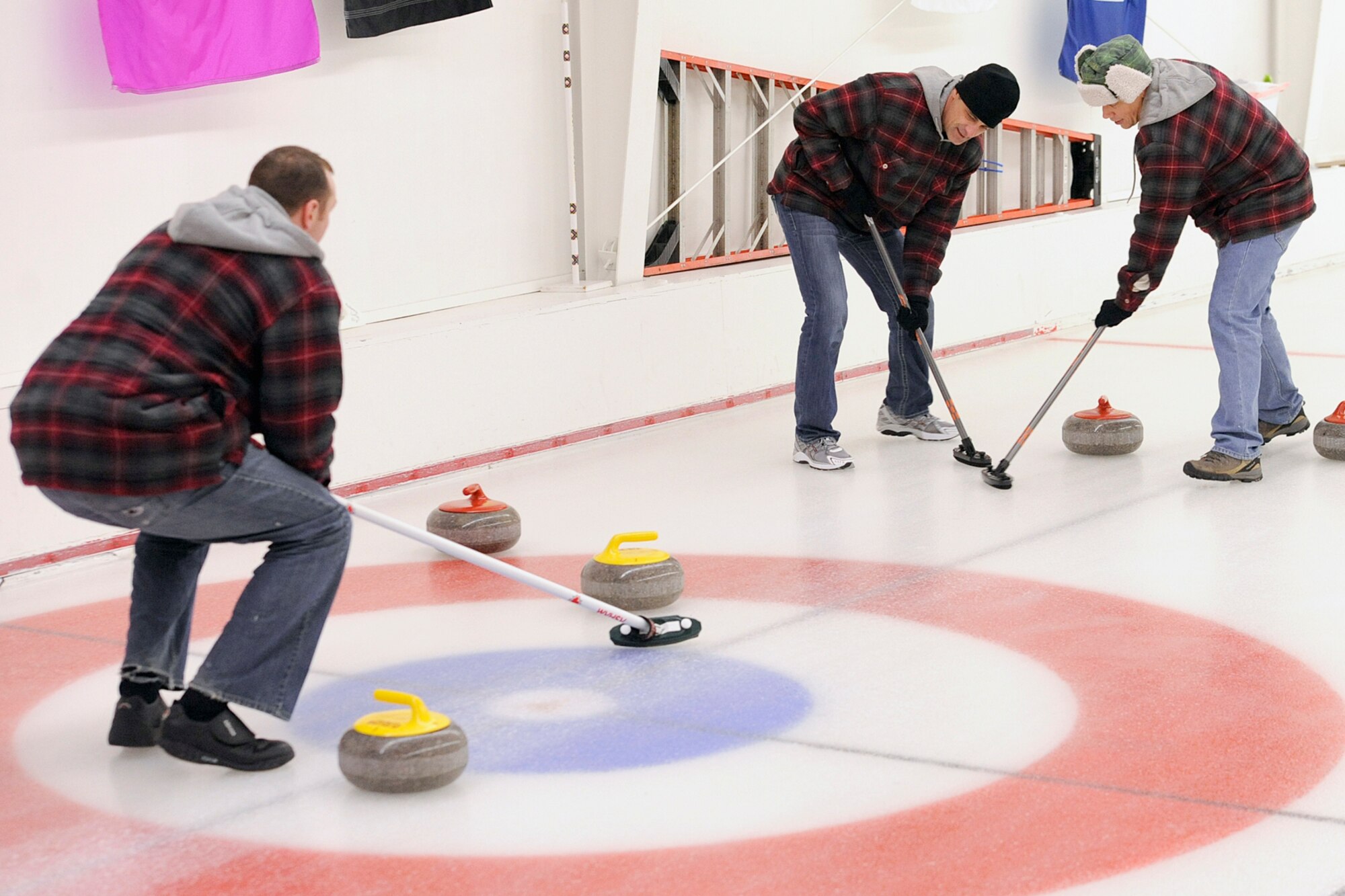 Sweepers from the 962nd Airborne Air Control Squadron guide a stone as it slides across the ice during the 3rd Wing curling competition March 2 at the Anchorage Curling Club. All eight 3rd Wing squadrons provided five-person teams to take part in the friendly competition.  (U.S. Air Force photo/John Pennell)