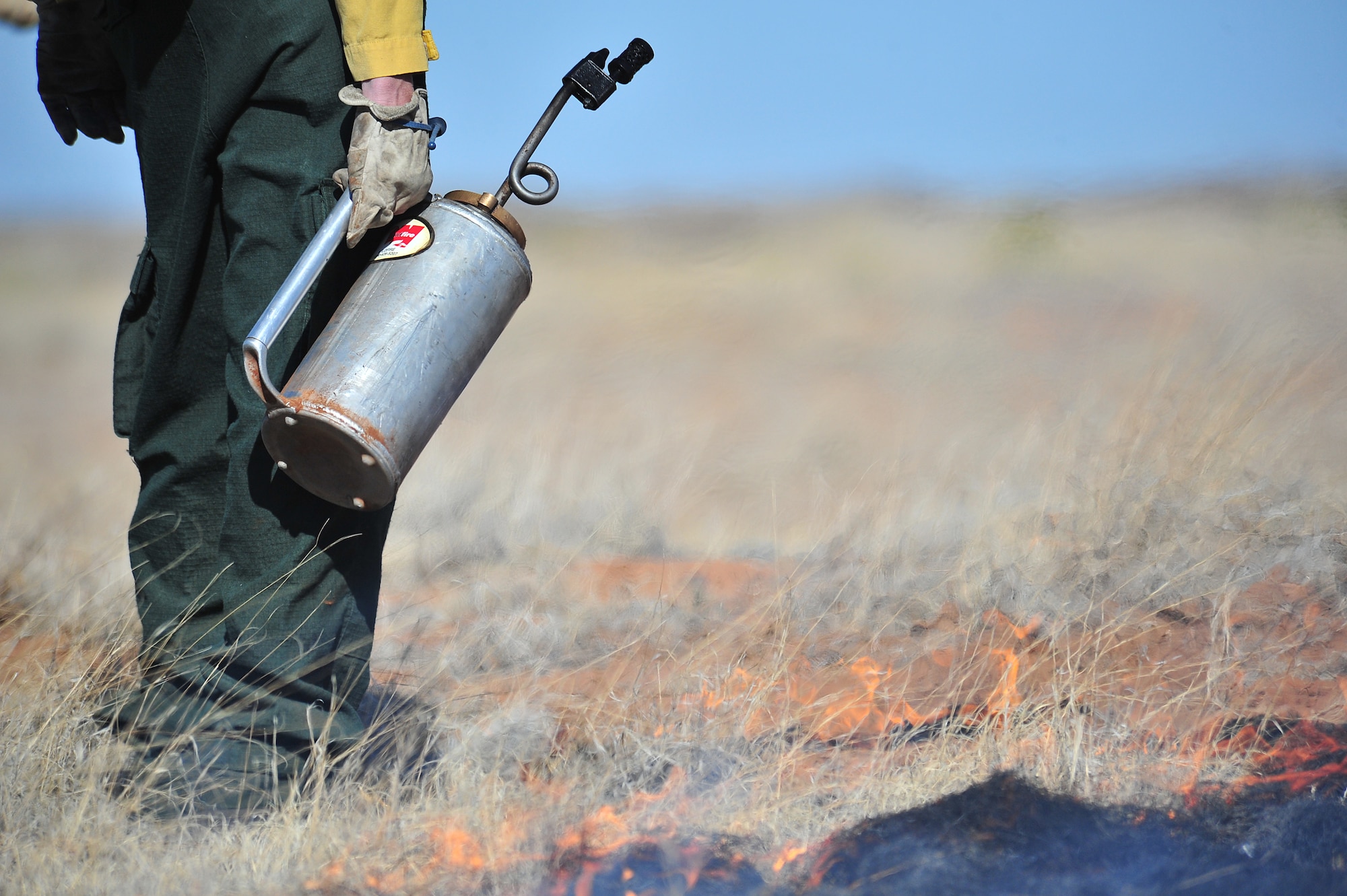 A Melrose Air Force Range firefighter uses a drip torch to start fires for a controlled burn, March 5, 2012. Controlled burns are used to deprive wild fires of fuel and to prevent them from spreading. Melrose Range provides a space for realistic training of ground and air forces and is operated by Cannon Air Force Base, N.M. (U.S. Air Force photo by Tech. Sgt. Josef Cole)