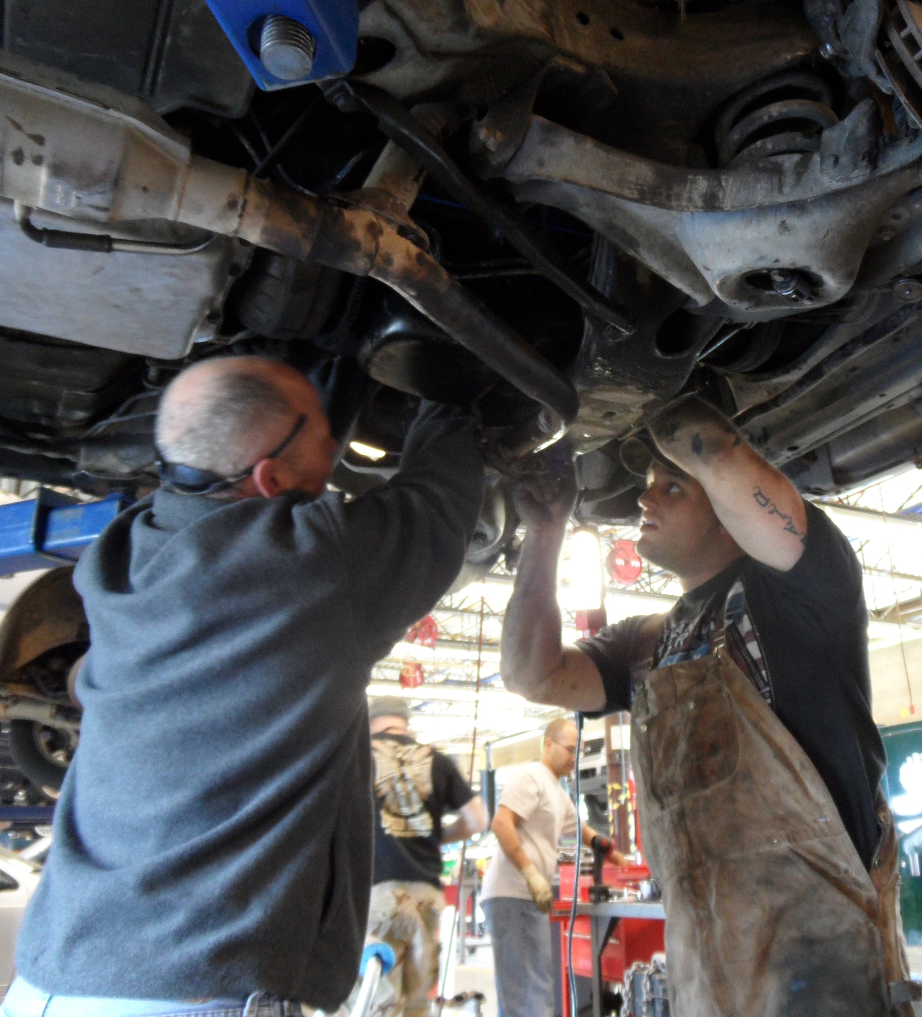 U.S. Air Force Staff Sgt. J.T. Oswald (right) and Chief Master Sgt. Kenneth Karnes (left), both 355th Equipment Maintenance Squadron, put the finishing touches on the oil pan of a 1984 Chevy Caprice Classic at the Auto Hobby Shop on Davis-Monthan Air Force Base, Ariz., Feb. 4. Squadron members are restoring the car using their own skills and funds. It will be presented to Tech. Sgt. Adrian Mapps, 355th EMS, once it is complete. (Courtesy photo/Released)