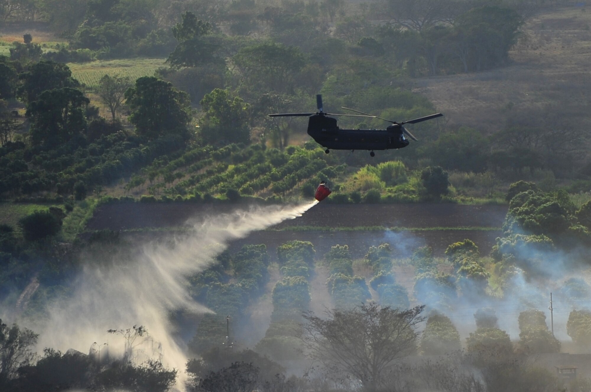 SOTO CANO AB, Honduras - A U.S. Army CH-47 Chinook assigned to 1st Battalion, 228th Aviation Regiment drops water on a brushfire 50 meters outside the perimeter of Soto Cano AB March 4 here. The brushfire, which started when an electrical line fell due to high winds, was extinguished with the combined efforts of the Joint Task Force-Bravo Fire Department, Comayagua Fire Department and the 228th AR. (U.S. Air Force photo/Staff Sgt. Bryan Franks) 