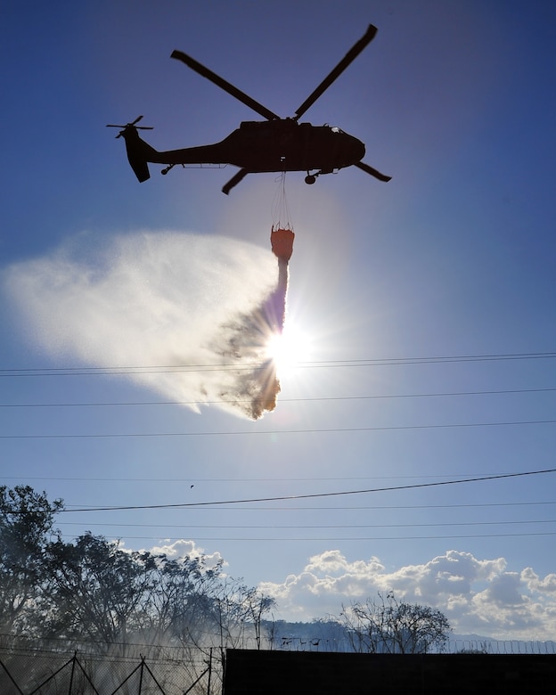 SOTO CANO AB, Honduras - A U.S. Army UH-60 Blackhawk assigned to 1st Battalion, 228th Aviation Regiment drops water on a brushfire 50 meters outside the perimeter of Soto Cano AB March 4 here. The brushfire, which started when an electrical line fell due to high winds, was extinguished with the combined efforts of the Joint Task Force-Bravo Fire Department, Comayagua Fire Department and the 228th. (U.S. Air Force photo/Staff Sgt. Bryan Franks) 