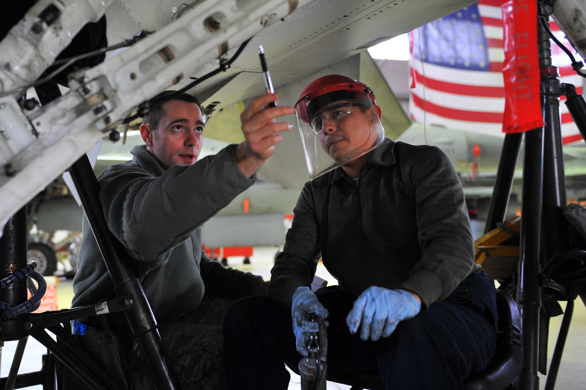 SPANGDAHLEM AIR BASE, Germany – Staff Sgt. Michael Selfridge, left, 52nd Maintenance Operations Squadron aircraft maintenance inspector, inspects Airman 1st Class Ramiro Gamero’s, 480th Fighter Squadron crew chief, work during an F-16 Fighting Falcon landing gear maintenance inspection inside Hangar 2 here March 8. The AMXS quality assurance section is made up of eight certified maintenance inspectors who inspect 81st and 480th Fighter Squadron aircraft maintenance processes. Quality assurance modernizes the Air Force’s aircraft maintenance and training by tracking maintenance performance against metrics to improve efficiency, production, and reliability.  (U.S. Air Force photo by Airman 1st Class Dillon Davis/Released)