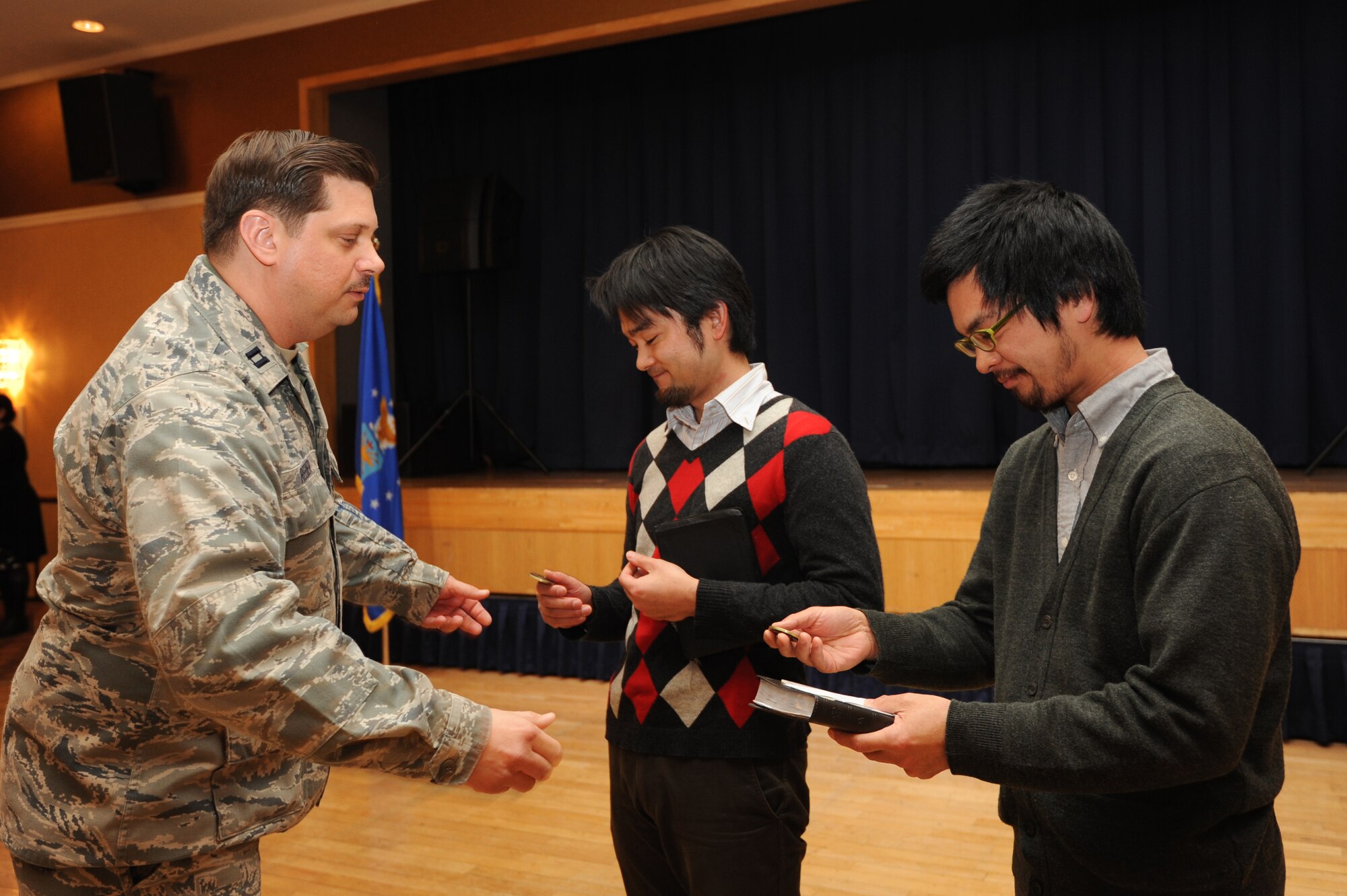 U.S. Air Force Capt. Christopher Reeder, 35th Fighter Wing chaplain, presents coins to guest speaker Yoshiya Kondo, center, Morioka Baptist Bible Church pastor, and Micah Ghent, Kondo's translator, during the National Prayer Luncheon at Misawa Air Base, Japan, March 7, 2012. The theme of this year's luncheon was, "One year later," referring to Japan's 2011 earthquake and subsequent tsunami. Kondo shared his experiences from the historical event. (U.S. Air Force photo by Airman 1st Class Kia Atkins/Released)