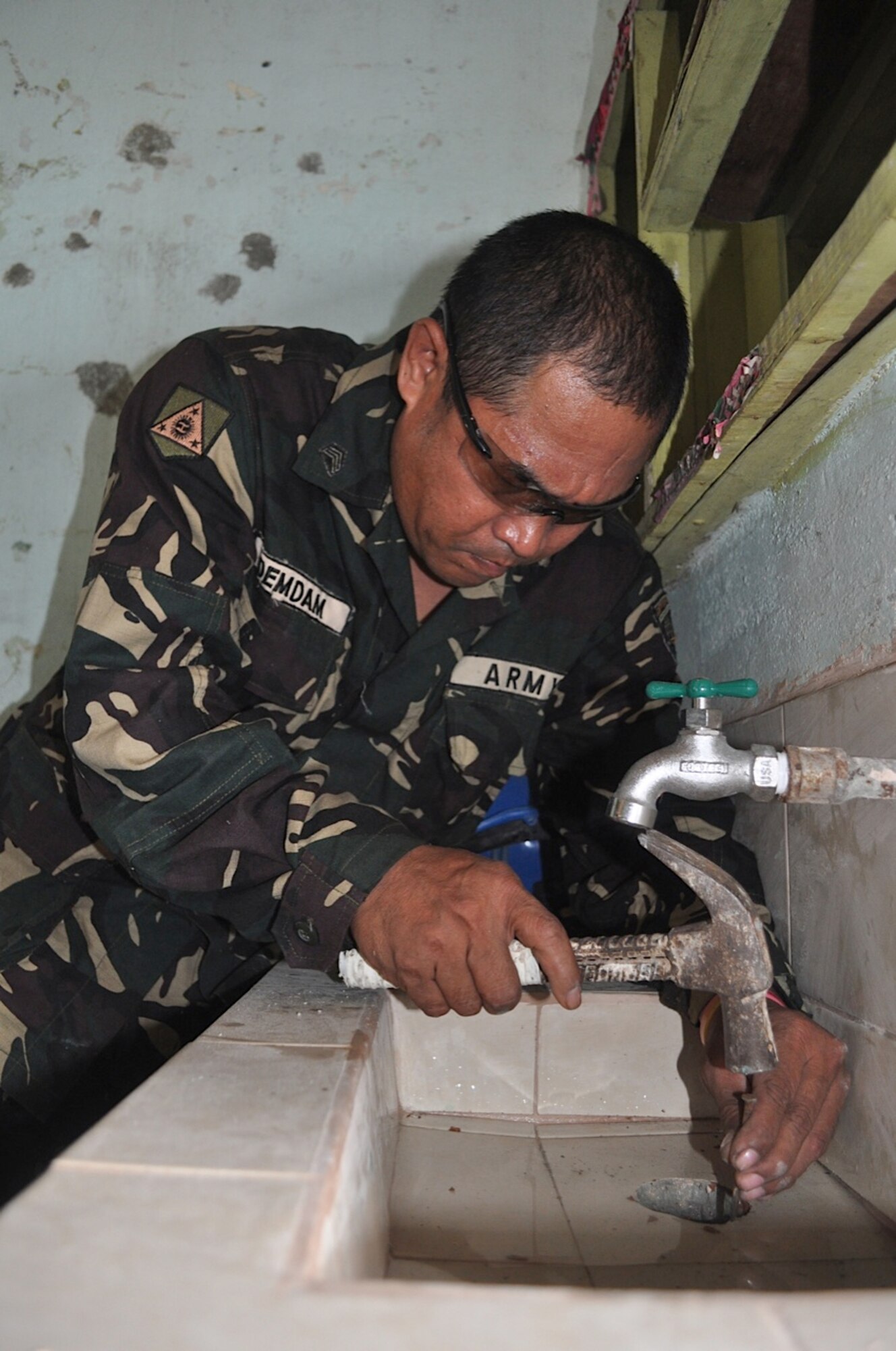 Philippines Army Sgt. Antonio Dendam master plumber and carpenter works on the drainage hole of a sink in one of the three classrooms March 5, 2012, at Binitayan Elementary School, Legazpi City, Philippines, during Operation Pacific Angel-Philippines. Dendam will work on two more sinks and replace toilets in each classroom during the next few days. PACANGEL is a joint and humanitarian operation. It is scheduled to run through March 10. (U.S. Air Force photo/Master Sgt. Allison Day)