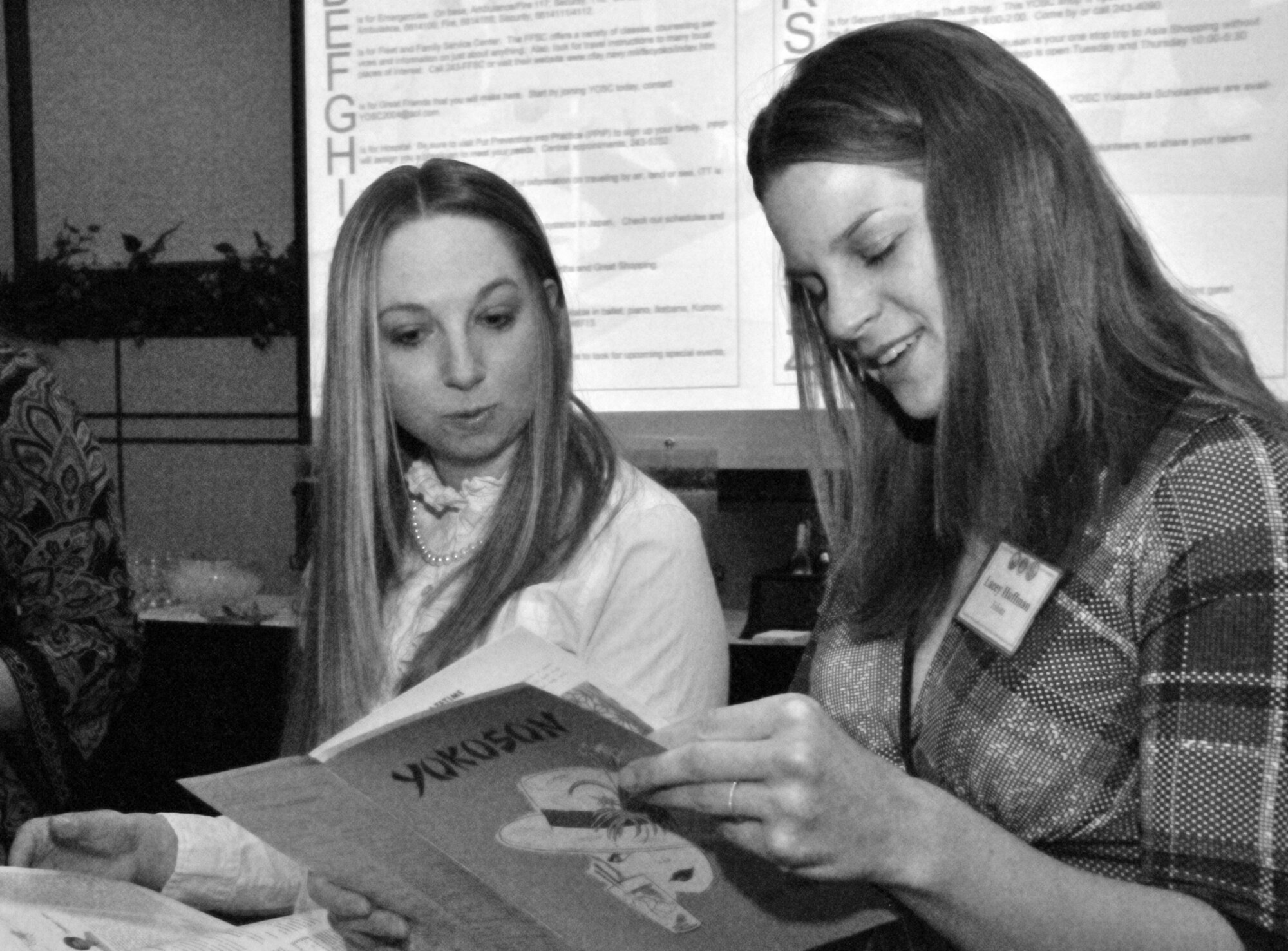 YOKOTA AIR BASE, Japan -- Chelsea Metros (left) and Lacey Huffman, members of the Yokota Officers Spouses Club, look at old flyers during the annual Tri-Service Luncheon at the Yokota Officer's Club, Feb. 28, 2012. The Tri-Service luncheon brings together the officers spouses clubs from Yokota, Atsugi Naval Air Facility, Camp Zama Army Post and Yokosuka Naval Base. This year's luncheon was themed "Looking Back, Moving Forward," and featured guest speaker Gwen Fujie. (U.S. Air Force photo/Airman 1st Class Desiree Economides)