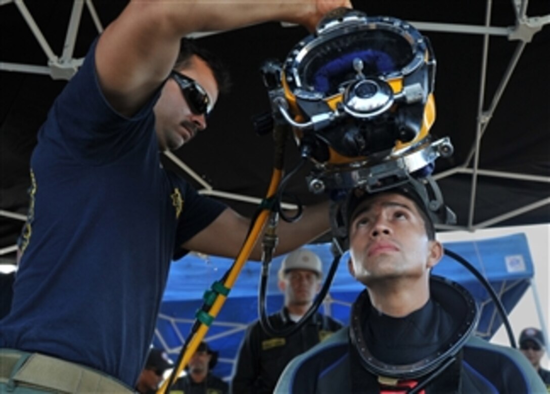 U.S. Navy Petty Officer 3rd Class Richard Burby, assigned to Mobile Diving and Salvage Unit 2, Company 2-1, places a KM 37 dive helmet onto Colombian navy diver Jimenez Espinel Robinson in Cartagena, Colombia, on March 1, 2012.  Company 2-1 is supporting Navy Dive-Southern Partnership Station 2012, a multinational partnership engagement designed to increase interoperability and partner nation capacity through diving operations.  