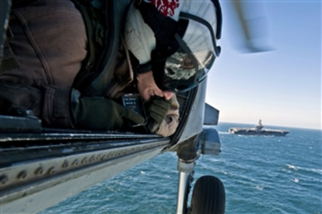 U.S. Navy Petty Officer Hospital Corpsman 2nd Class Richard O'Dell guides the pilots of an HH-60H Sea Hawk helicopter as they retrieve cargo from the deck of the fast combat support ship USNS Bridge during a replenishment-at-sea mission with the aircraft carrier USS Carl Vinson under way in the Persian Gulf, March 6, 2012. O'Dell is a hospital corpsman assigned to Helicopter Anti-Submarine Squadron 15.