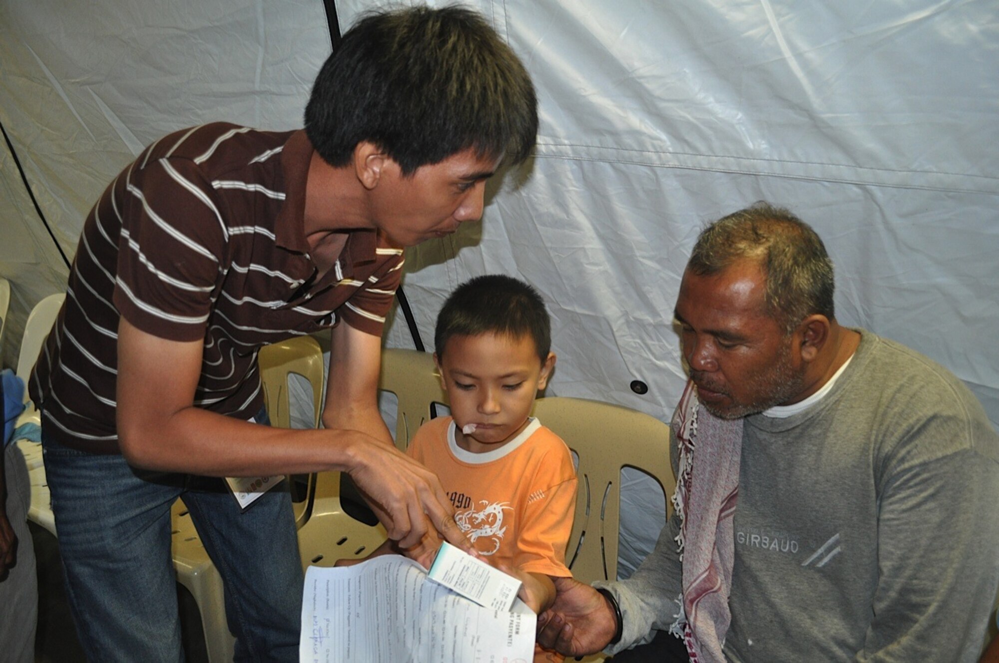 Six-year old, Arlie John Cimane s, looks on as his father, Eduardo Zoeta Cimanes, receives medication for him from a volunteer in Legazpi City, Philippines, March 8, 2012. Arlie is one of the lucky ones to have an appointment for medical care during Operation Pacific Angel-Philippines March 5 through 10. There were hundreds of walk ins for the joint and combined humanitarian operation, which include medical, dental, optometry, engineering support and subject-matter expert exchanges. (U.S. Air Force photo/Master Sgt. Allison Day) 