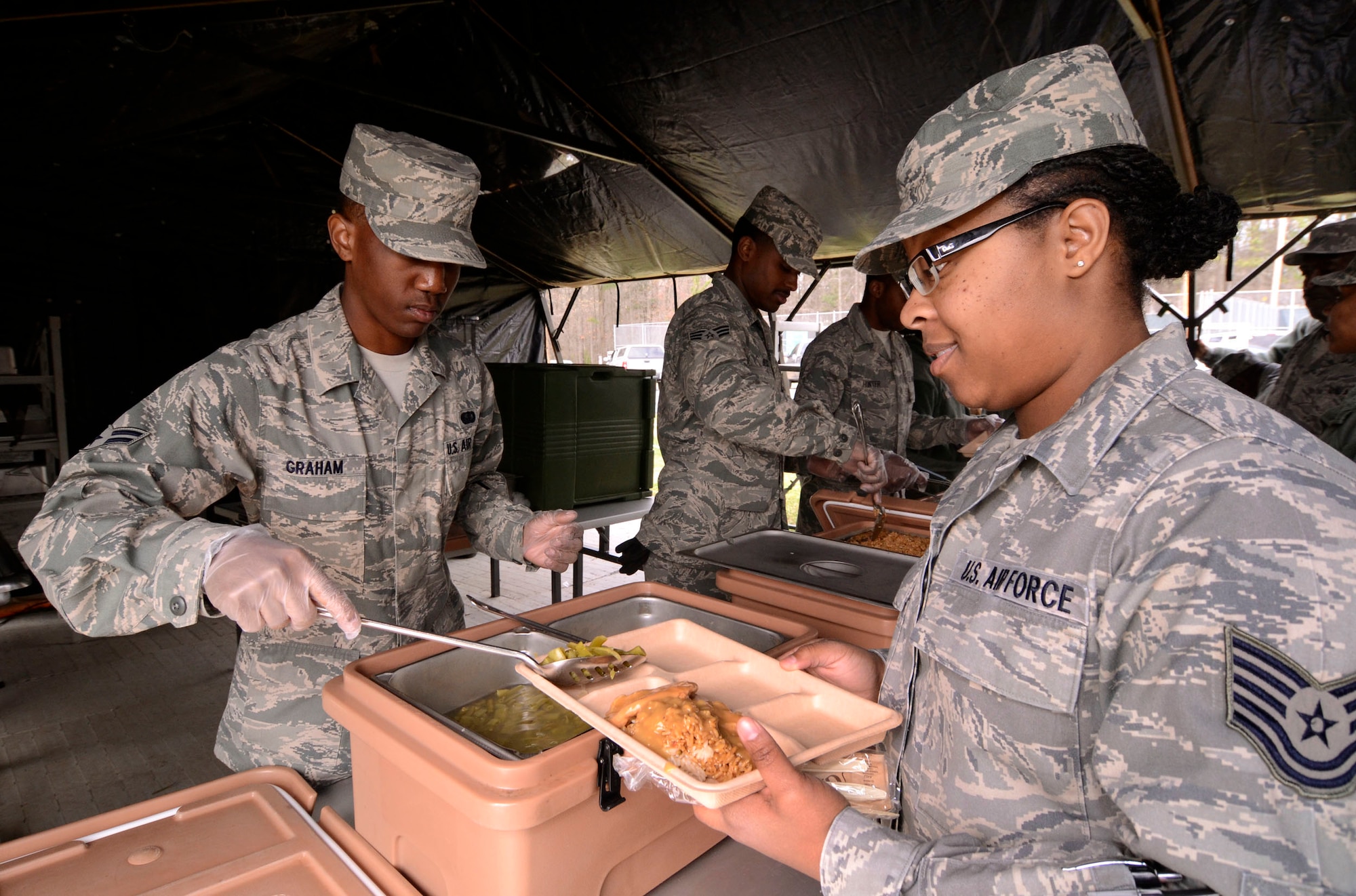 Airman 1st Class Darius Graham serves hot green beans to Tech. Sgt. Tech. Sgt. Rosilyn Johnson in the 94th Force Support Squadron’s Single Pallet Expeditionary Kitchen (SPEK) at Dobbins Air Reserve Base, Ga., March 7. Reservist with the 94th FSS performed and received annual tour training throughout the week in order to stay proficient or upgrade their specialized Air Force skills. (U.S. Air Force photo/ Brad Fallin)