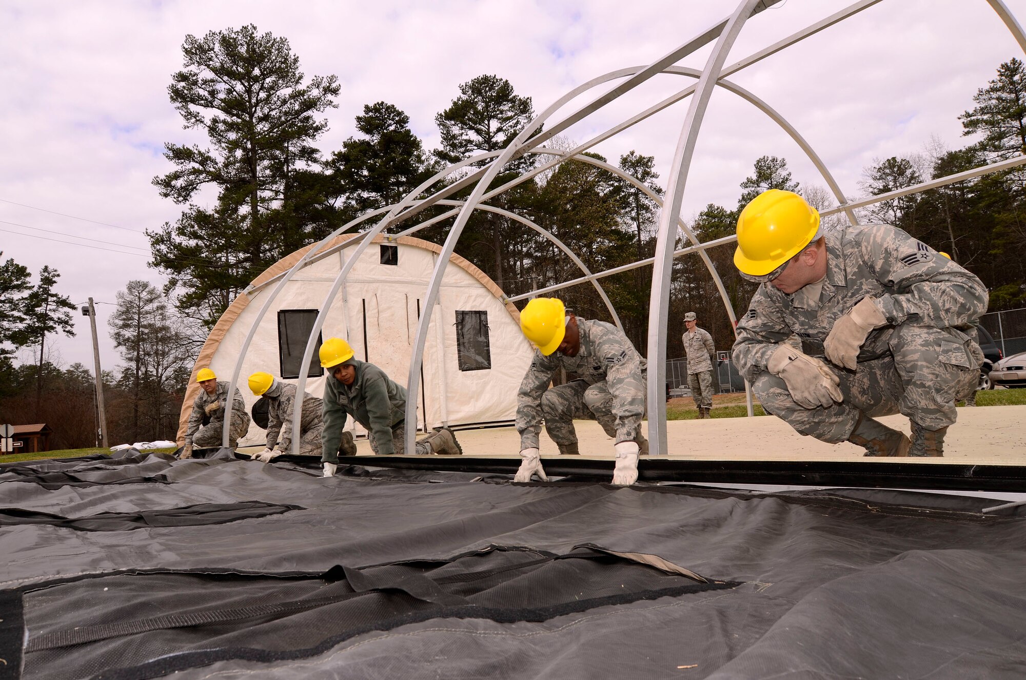 94th Force Support Squadron personnel attach the main canvas panel to the frame of the Alaska personnel shelter being setup at Dobbins Air Reserve Base, Ga, Mar. 7.  Reservist with the 94th FSS performed and received annual tour training throughout the week in order to stay proficient or upgrade their specialized Air Force skills. (U.S. Air Force photo/ Brad Fallin)