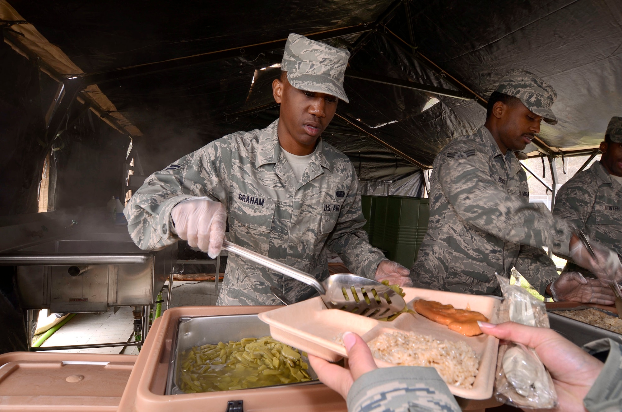 Airman 1st Class Darius Graham and Senior Airman Kenneth Beck serve food in the 94th Force Support Squadron’s Single Pallet Expeditionary Kitchen (SPEK) at Dobbins Air Reserve Base, Ga, Mar. 7. Reservist with the 94th FSS performed and received annual tour training throughout the week in order to stay proficient or upgrade their specialized Air Force skills. (U.S. Air Force photo/ Brad Fallin)