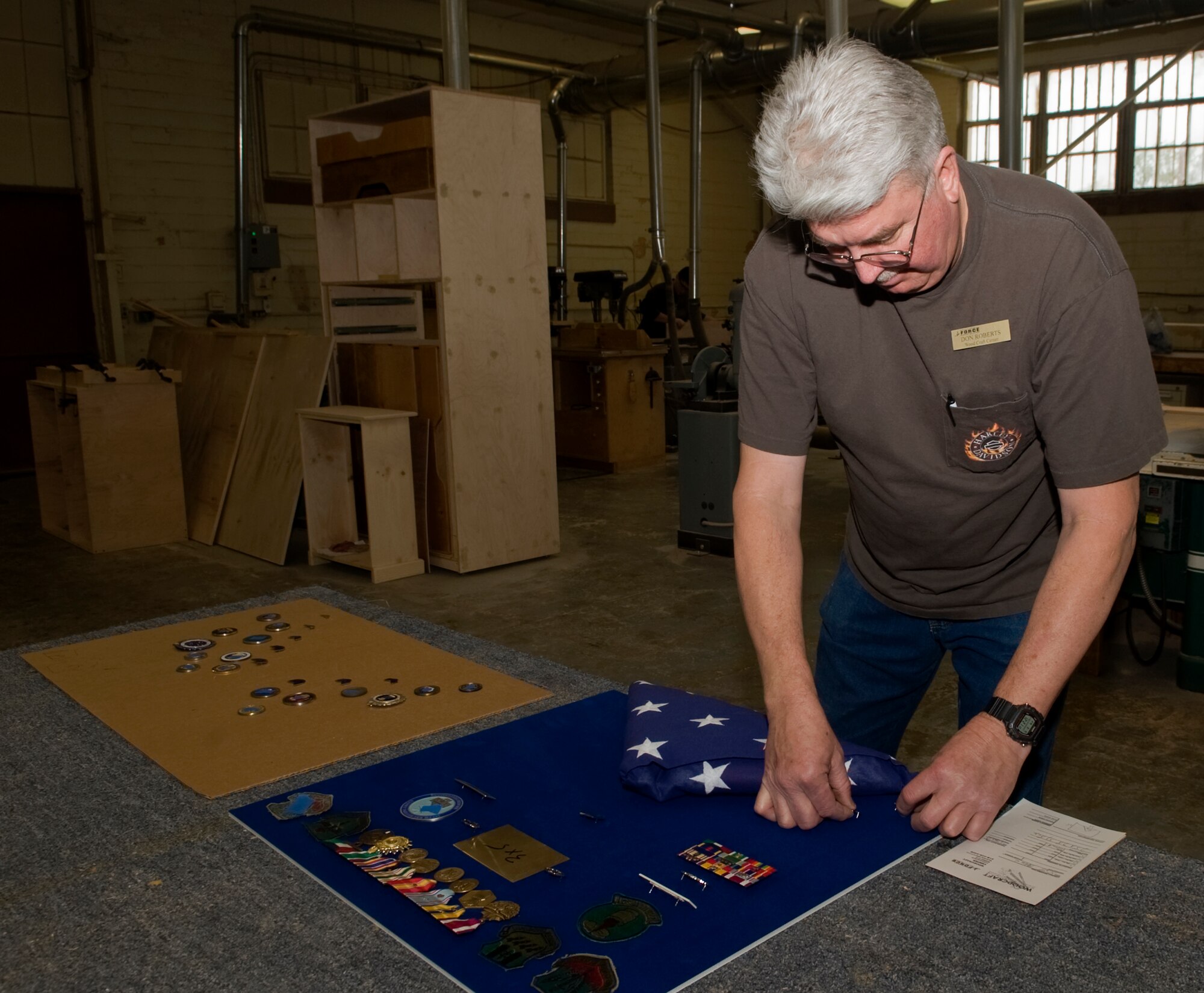 Don Roberts, 2nd Force Support Squadron Wood Craft Center assistant manager, places medals and decorations for a shadow box on a velvet background on Barksdale Air Force Base, La., March 9. Roberts helps build five to eight shadow boxes per week. Usually created for retirements, the wood shop offers custom-built shadow boxes as well as coin racks, signs, bookshelves and anything built from wood. (U.S. Air Force photo/Senior Airman Kristin High)(RELEASED) 