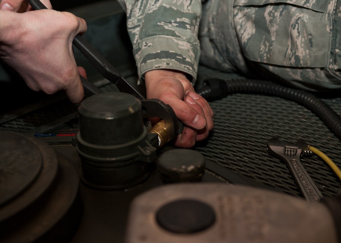 Senior Airman Phillip Laugle (left) and Airman 1st Class Ryan Harris, 28th Logistics Readiness Squadron refueling maintenance technicians, remove a hose from a manhole cover during preventative maintenance at Ellsworth Air Force Base, S.D., March 8, 2012. To remove the manhole cover, the hose had to be disconnected from an automatic shutoff probe called the high-high probe. (U.S. Air Force photo by Airman Alystria Maurer/Released)
