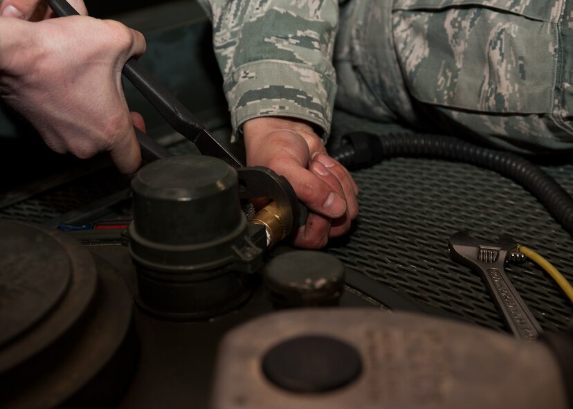 Senior Airman Phillip Laugle (left) and Airman 1st Class Ryan Harris, 28th Logistics Readiness Squadron refueling maintenance technicians, remove a hose from a manhole cover during preventative maintenance at Ellsworth Air Force Base, S.D., March 8, 2012. To remove the manhole cover, the hose had to be disconnected from an automatic shutoff probe called the high-high probe. (U.S. Air Force photo by Airman Alystria Maurer/Released)