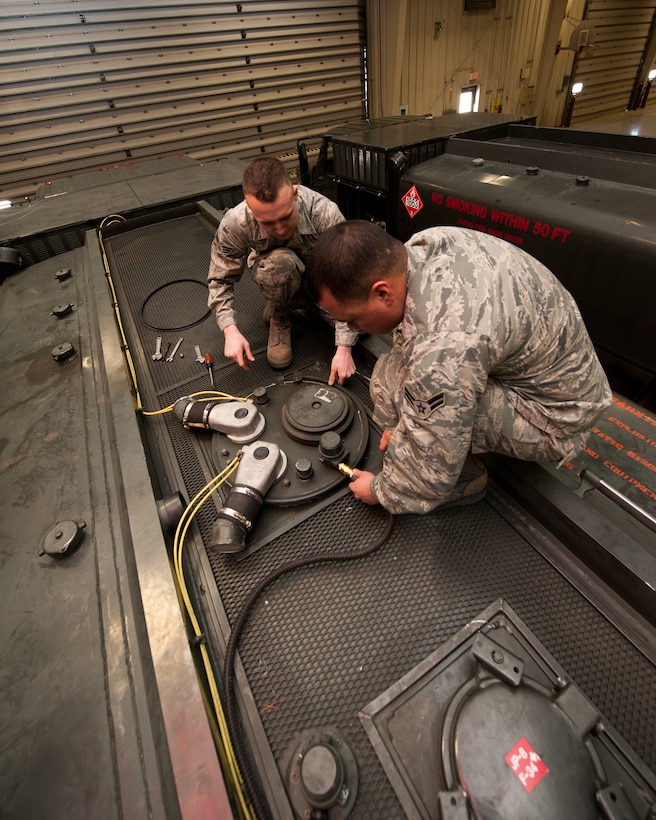 Senior Airman Phillip Laugle (left) and Airman 1st Class Ryan Harris, 28th Logistics Readiness Squadron refueling maintenance technicians, remove the cover from a fueling truck during preventative maintenance at Ellsworth Air Force Base, S.D., March 8, 2012. This manhole cover was removed to replace the seal which prevents fuel from overflowing out of the tank. (U.S. Air Force photo by Airman Alystria Maurer/Released)