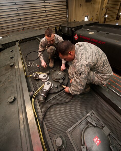 Senior Airman Phillip Laugle (left) and Airman 1st Class Ryan Harris, 28th Logistics Readiness Squadron refueling maintenance technicians, remove the cover from a fueling truck during preventative maintenance at Ellsworth Air Force Base, S.D., March 8, 2012. This manhole cover was removed to replace the seal which prevents fuel from overflowing out of the tank. (U.S. Air Force photo by Airman Alystria Maurer/Released)